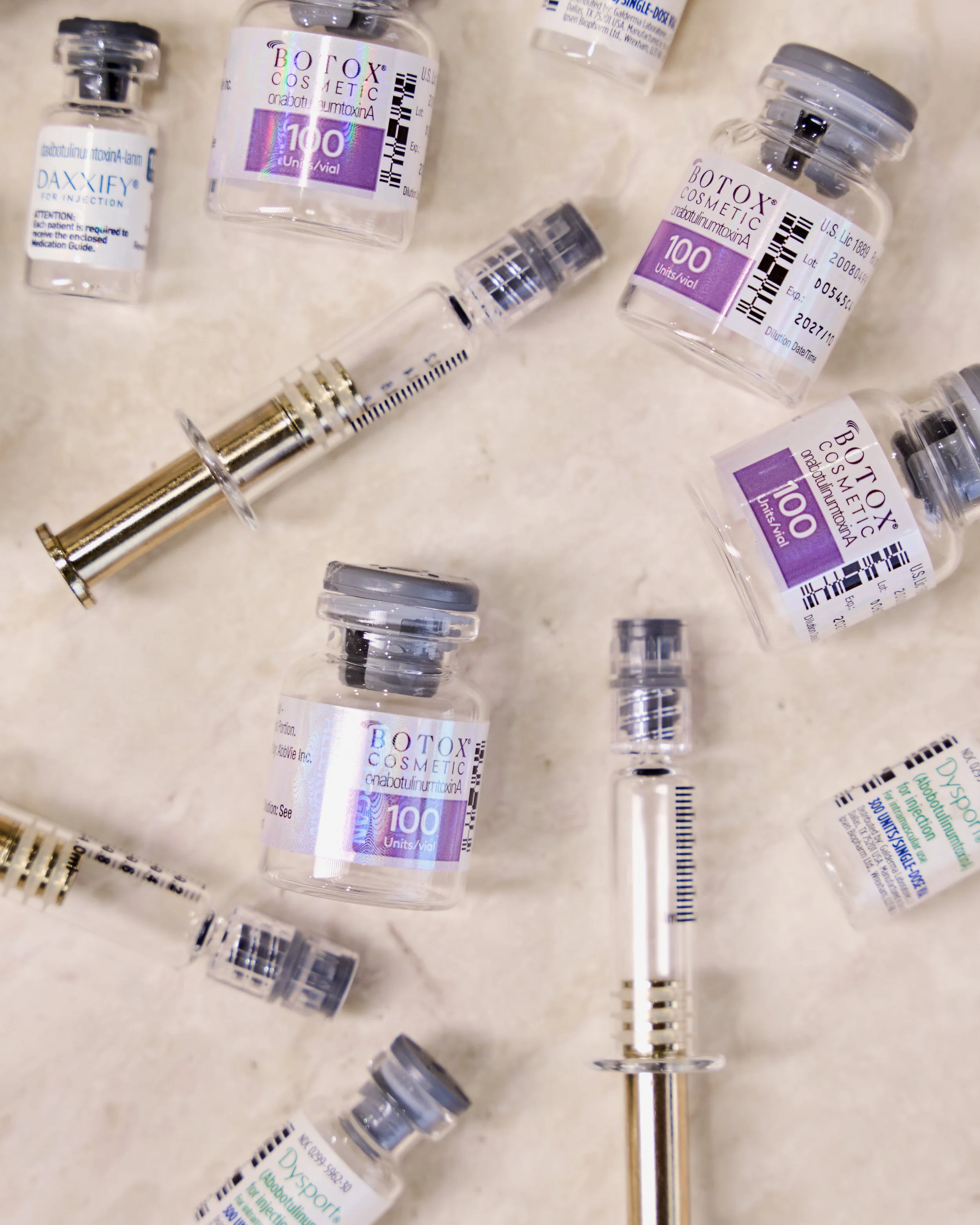 A syringe filled with brown pills on a pink background.