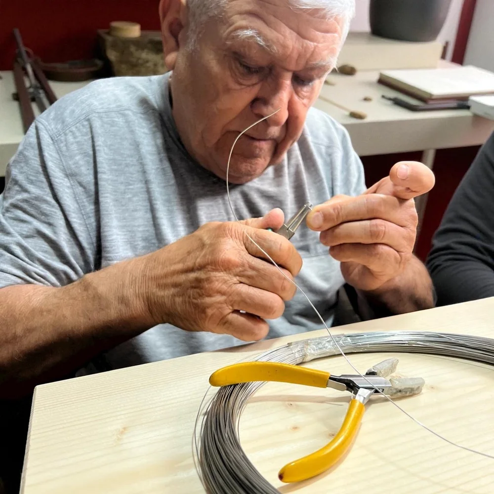 Artesano de NM Joyería trabajando alambre con pinzas en el taller familiar de Ensenada