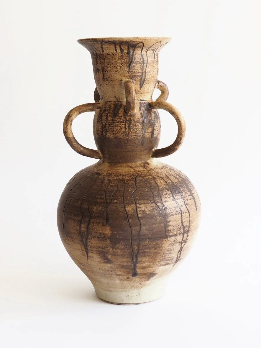 Ceramic vase with two handles, brown glaze with black drip patterns, on a white background.