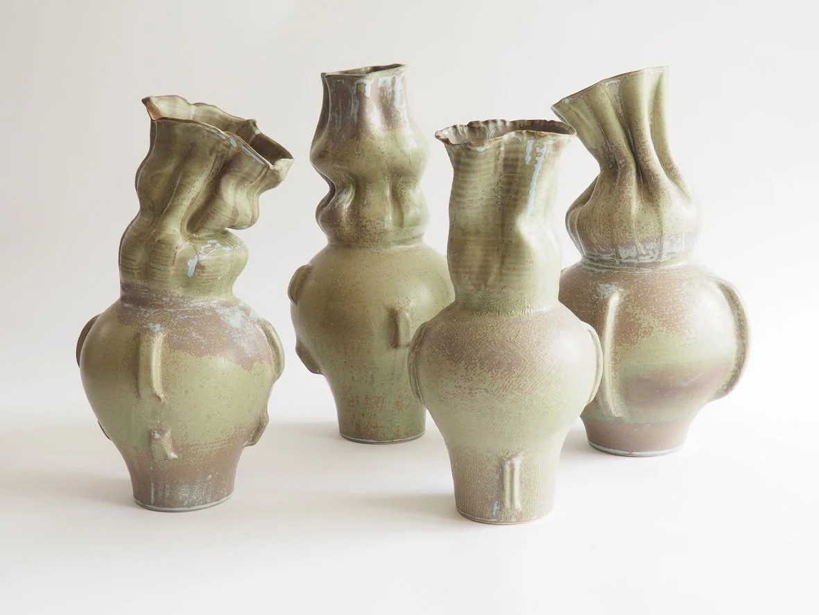 Four ceramic vases with textured, abstract shapes and muted earth tones on a white background.