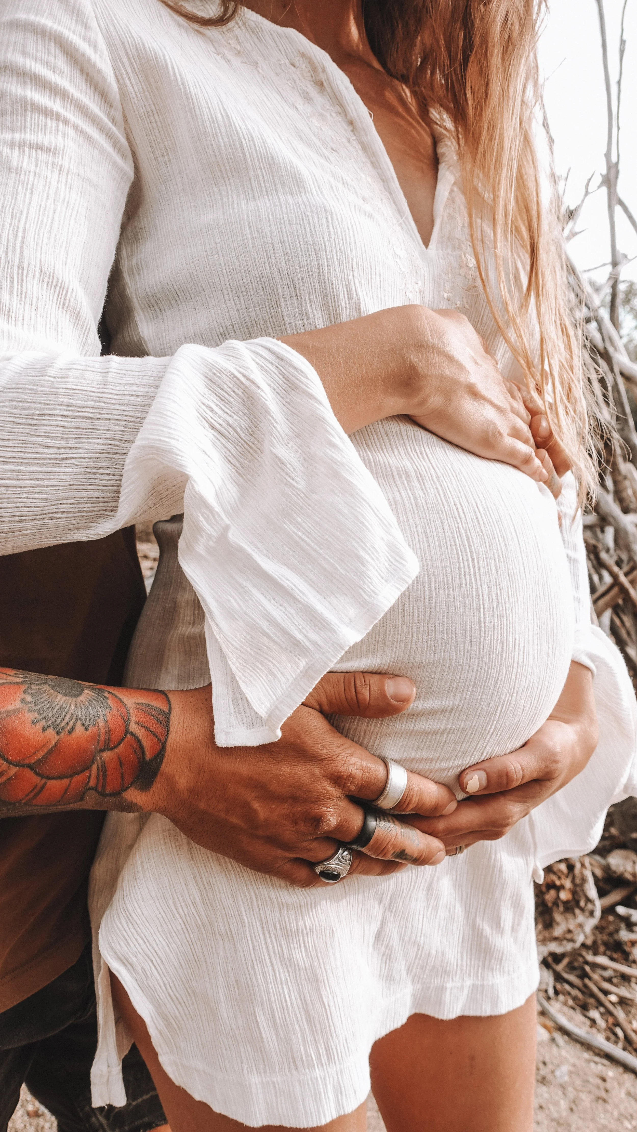 A pregnant woman and her partner, hugging.