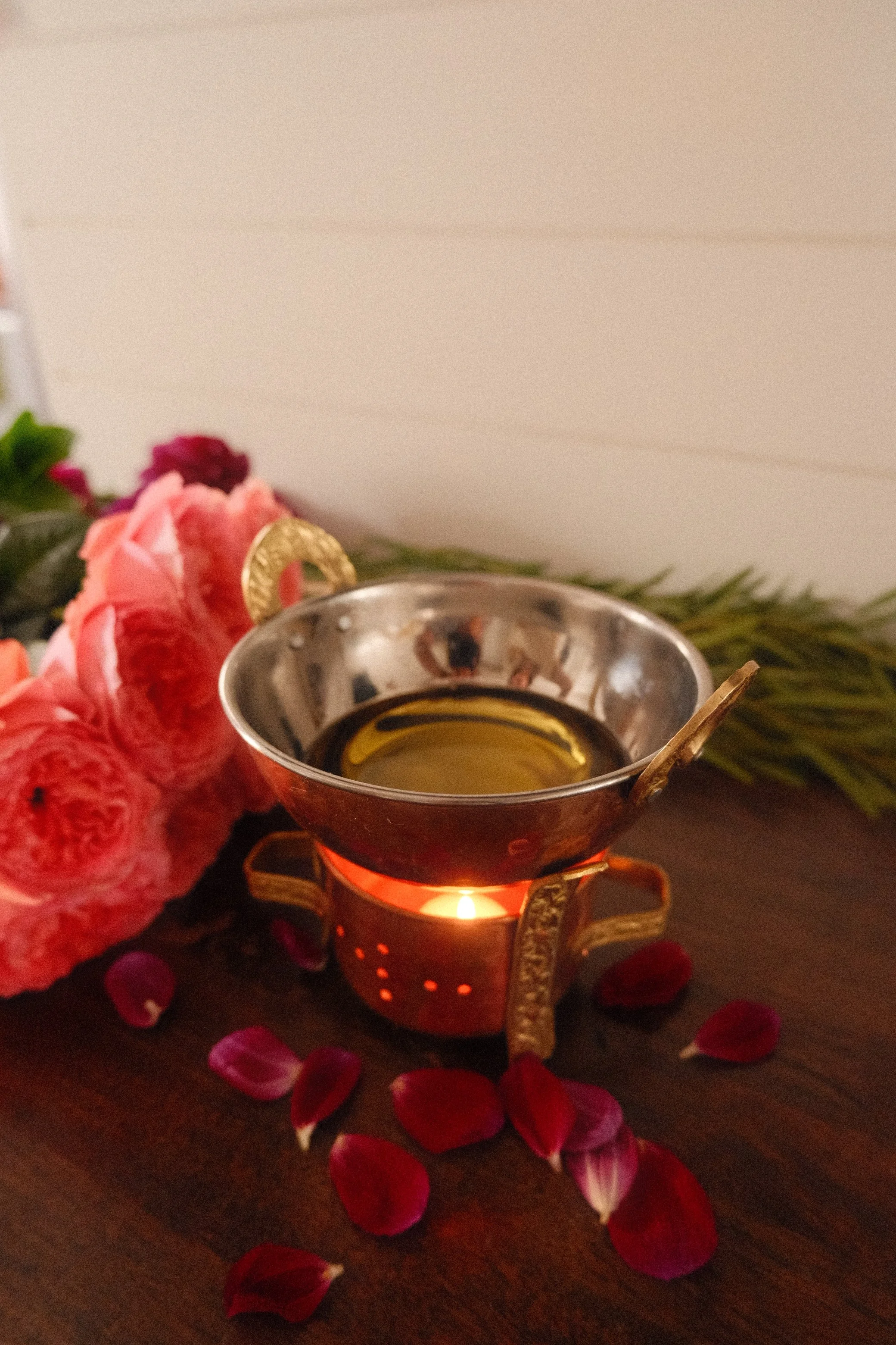 A small oil lamp for abhyanga massage, sits on a table.