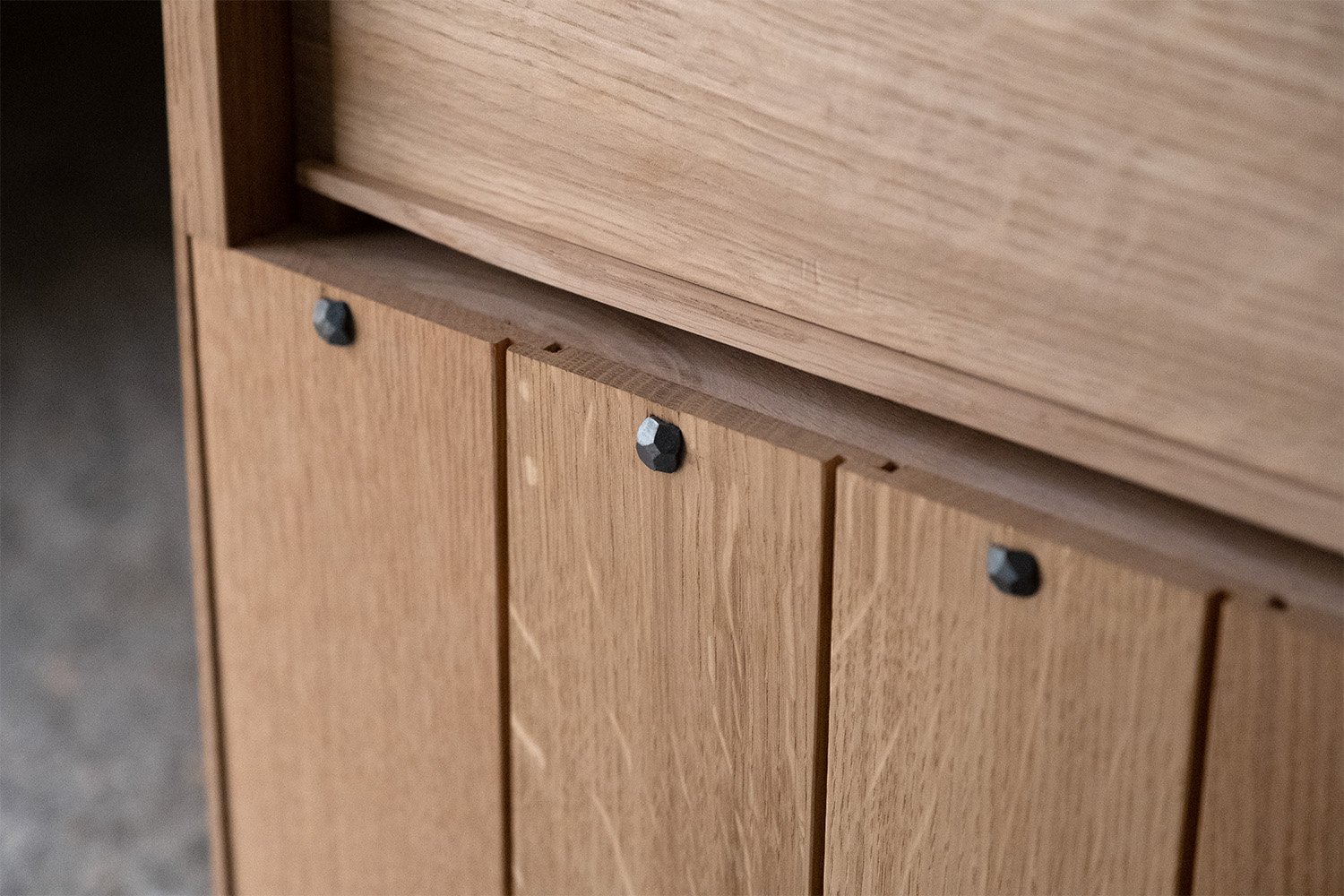 Oak back panels of the bedside cabinet secured with dark hand-forged nails.
