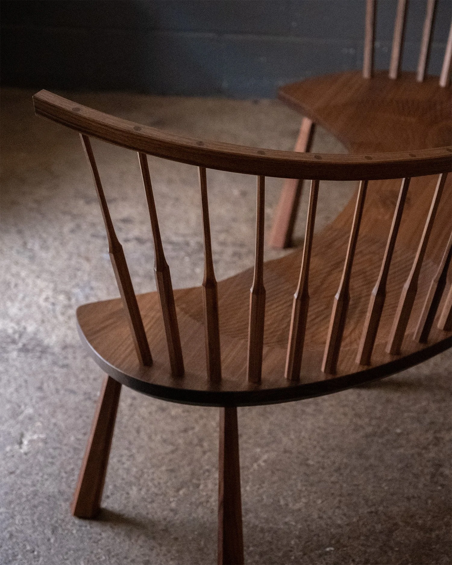 Detail of the curved walnut settee’s carved seat and spindles