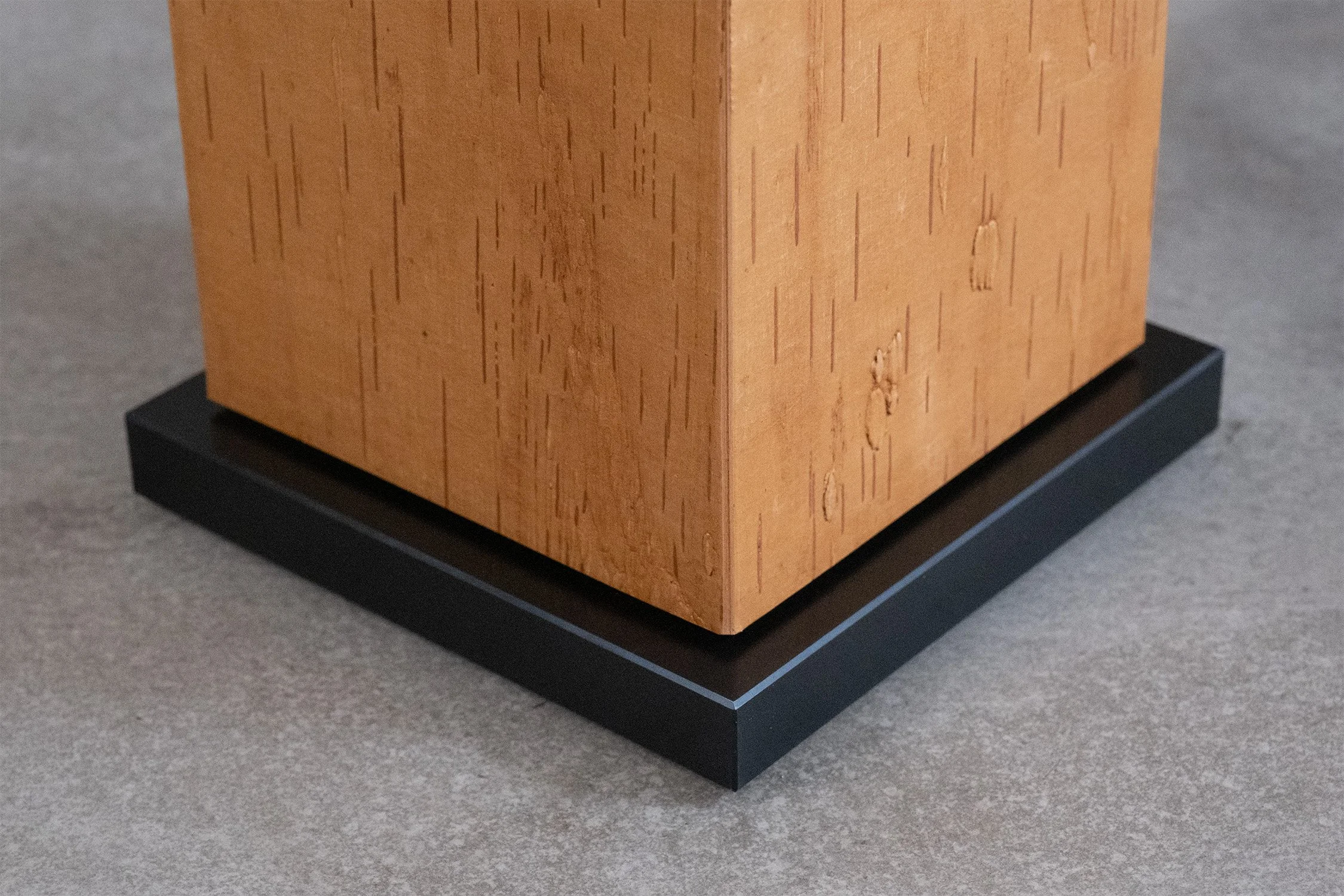Corner detail of a birch bark side table’s rectangular pedestal and black square plinth