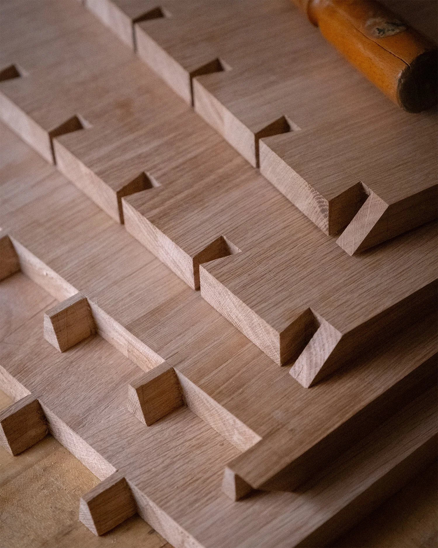 Hand-cut dovetail joints in oak cabinet components laid out on the workbench before assembly.