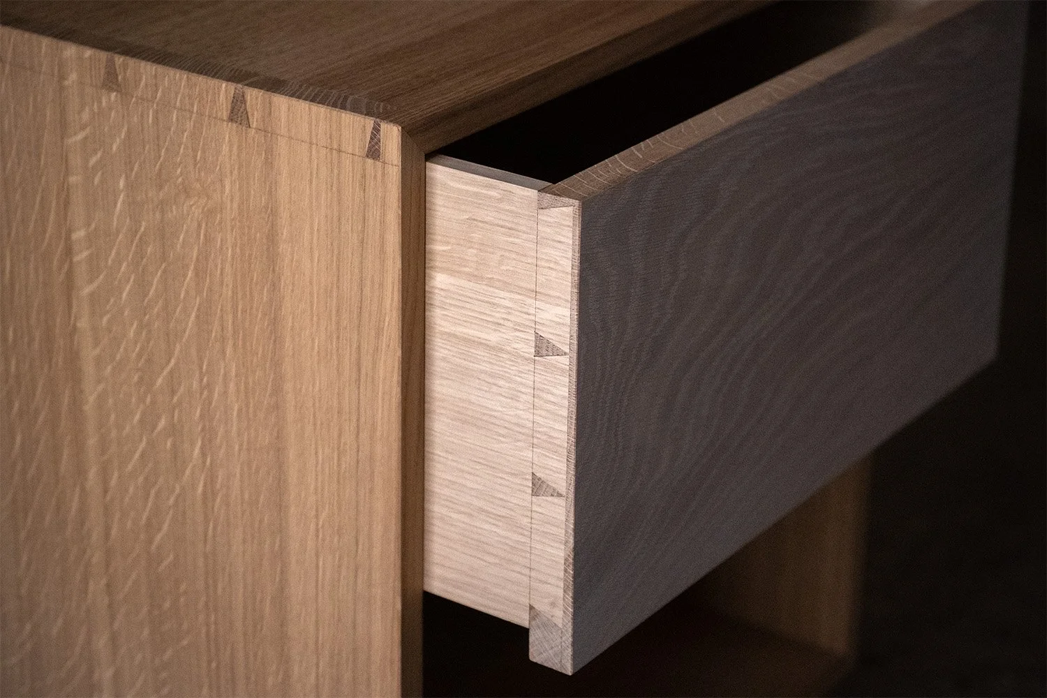 Open drawer of the oak bedside cabinet, showing fine dovetail joints and the whitewashed drawer front.