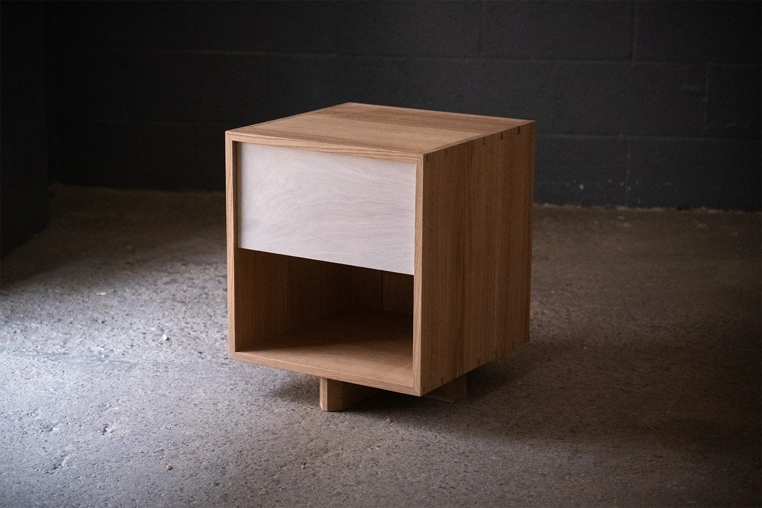 Handmade oak bedside cabinet with a whitewashed drawer front, open lower shelf and low timber feet.
