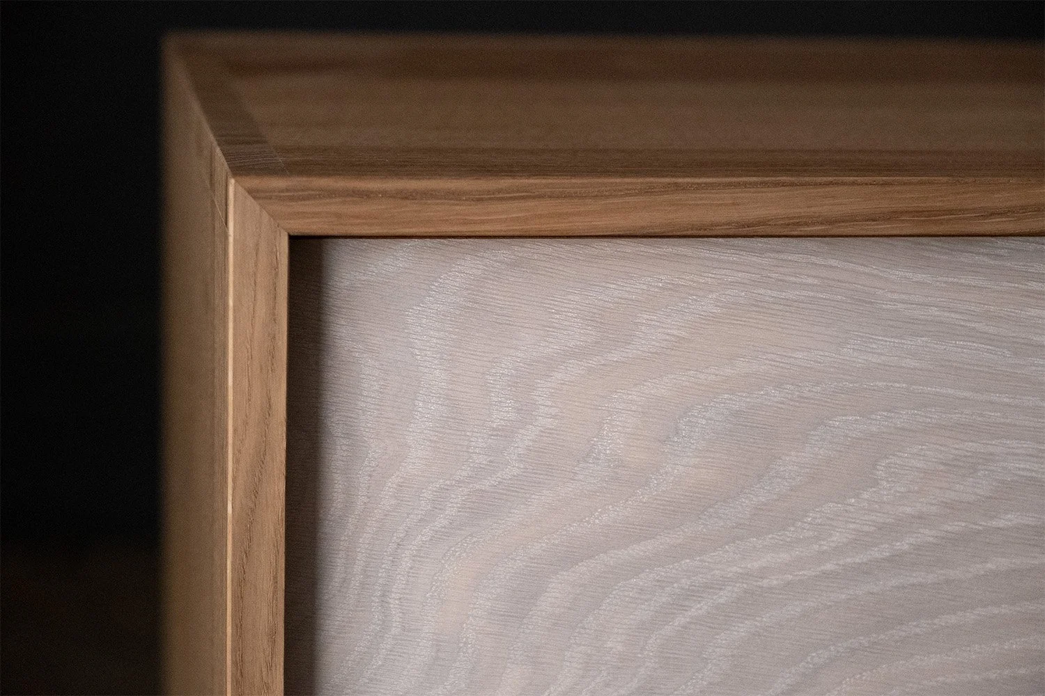 Close-up of the whitewashed oak drawer front fitted beneath the natural oak top of the bedside cabinet.
