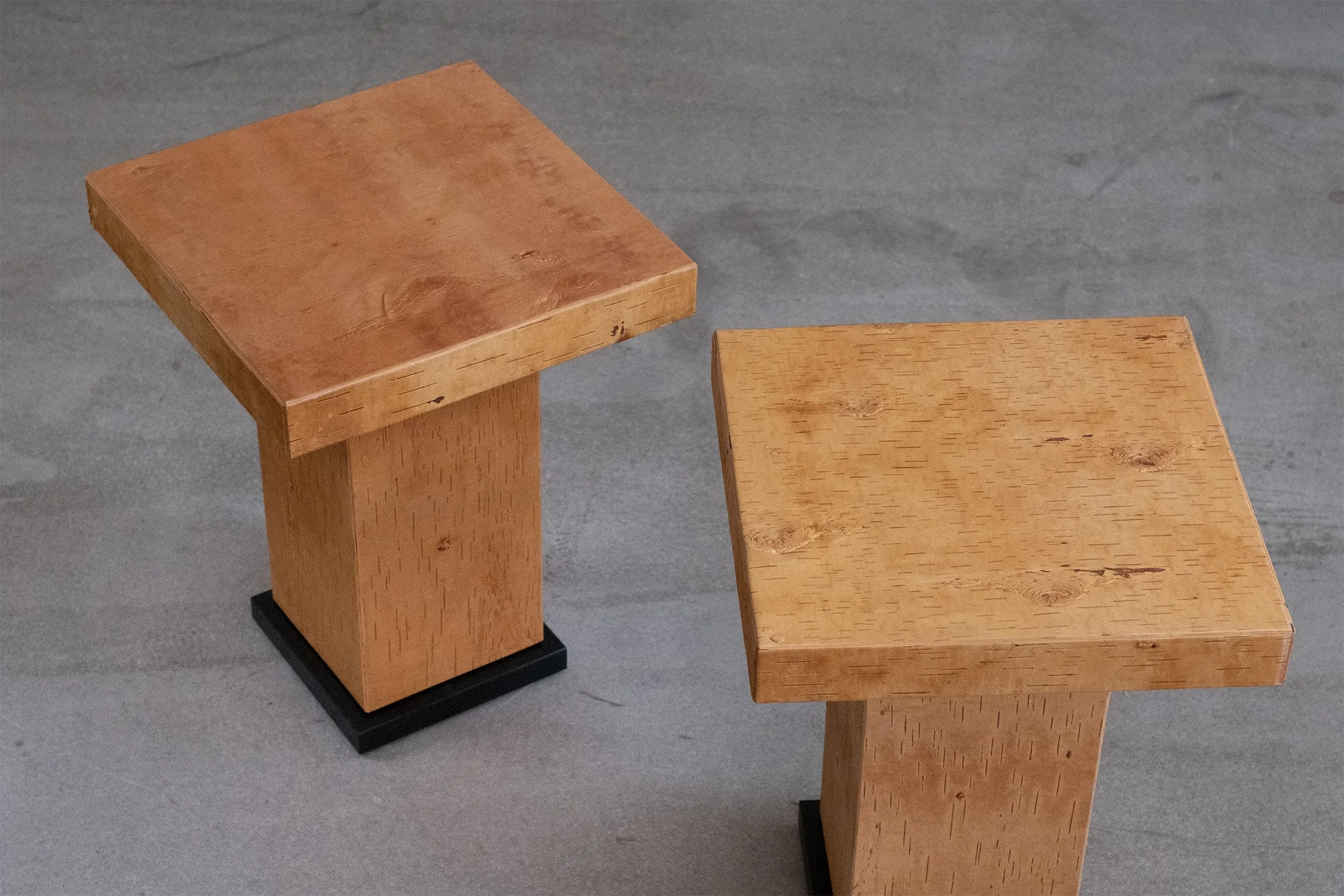 Elevated view of two birch bark side tables showing their square tops and natural surface markings