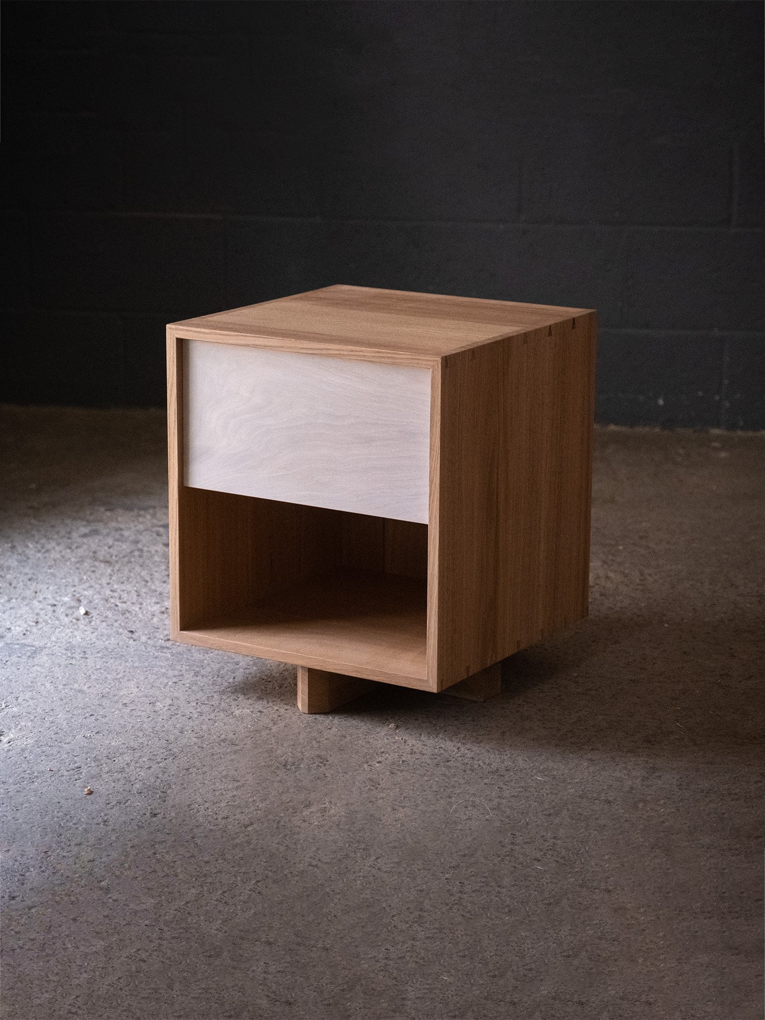 Handmade oak bedside cabinet with a whitewashed drawer front, open lower shelf and low timber feet.