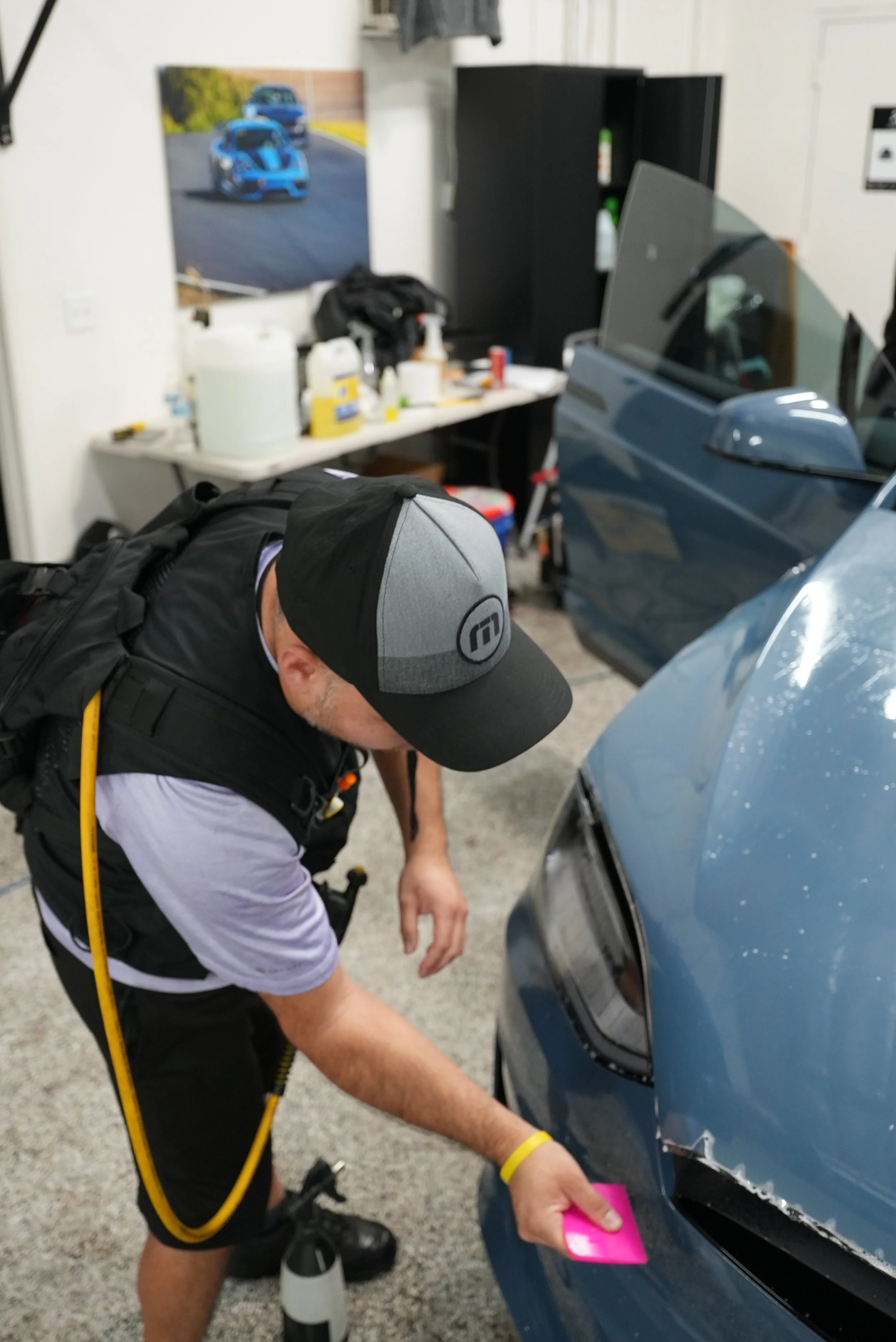 Professional paint protection film and ceramic coating inspection on a blue vehicle inside a controlled workshop in Campbell, showcasing premium vehicle protection services by Enthusiast Auto Tint for luxury and performance cars.