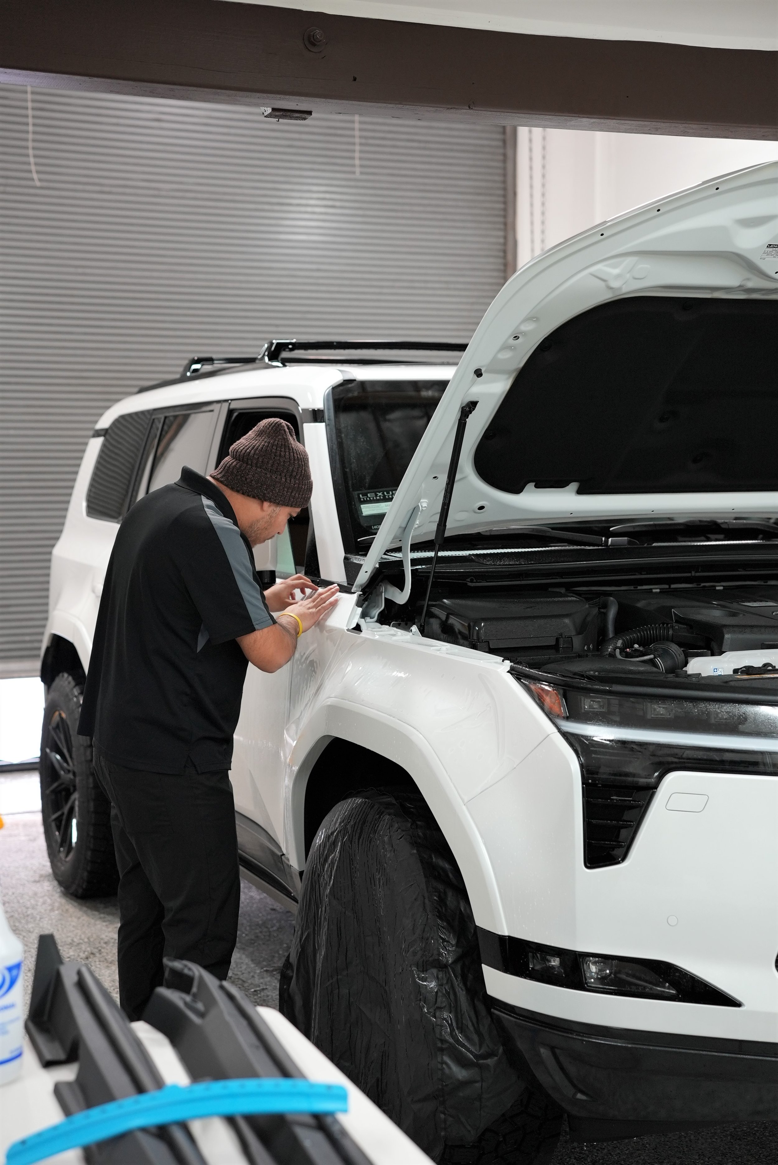 Professional paint protection film and ceramic coating installation on a white vehicle in a controlled workshop environment at Enthusiast Auto Tint in Campbell, specializing in luxury, Tesla, and high-end vehicle protection services.
