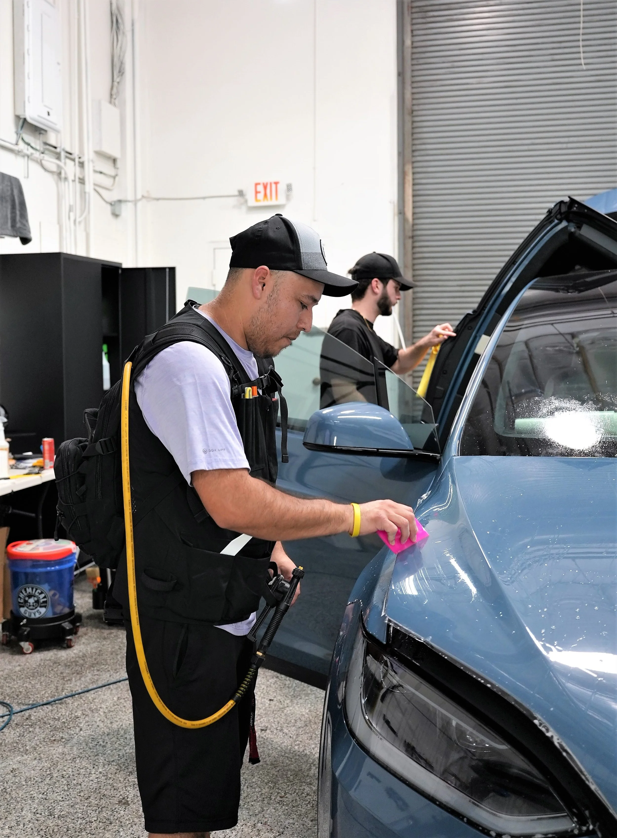 Professional paint protection film and ceramic coating installation on a blue vehicle inside a controlled automotive workshop in Campbell, showcasing premium detailing, precision installation, and luxury vehicle protection services by Enthusiast Auto