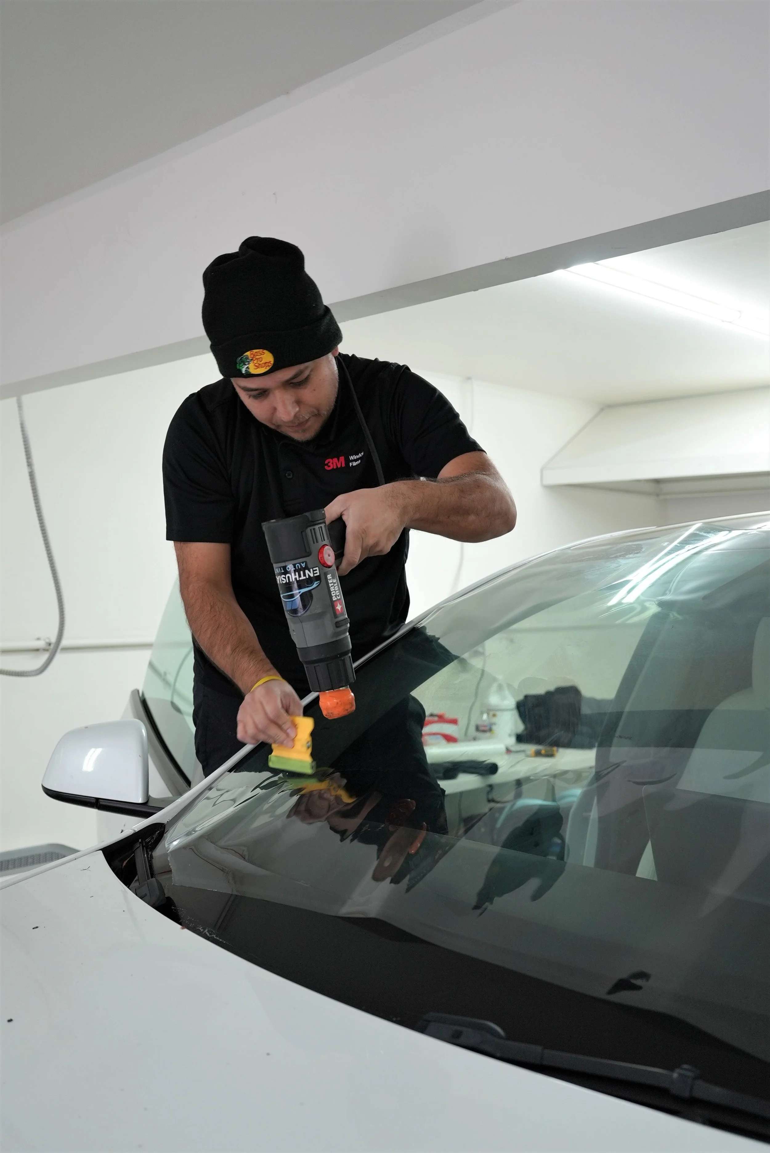 Professional ceramic window tint installation on a vehicle windshield using precision heat-shrinking techniques inside a controlled automotive workshop in Campbell, specializing in premium Tesla, luxury, and performance vehicle protection services by