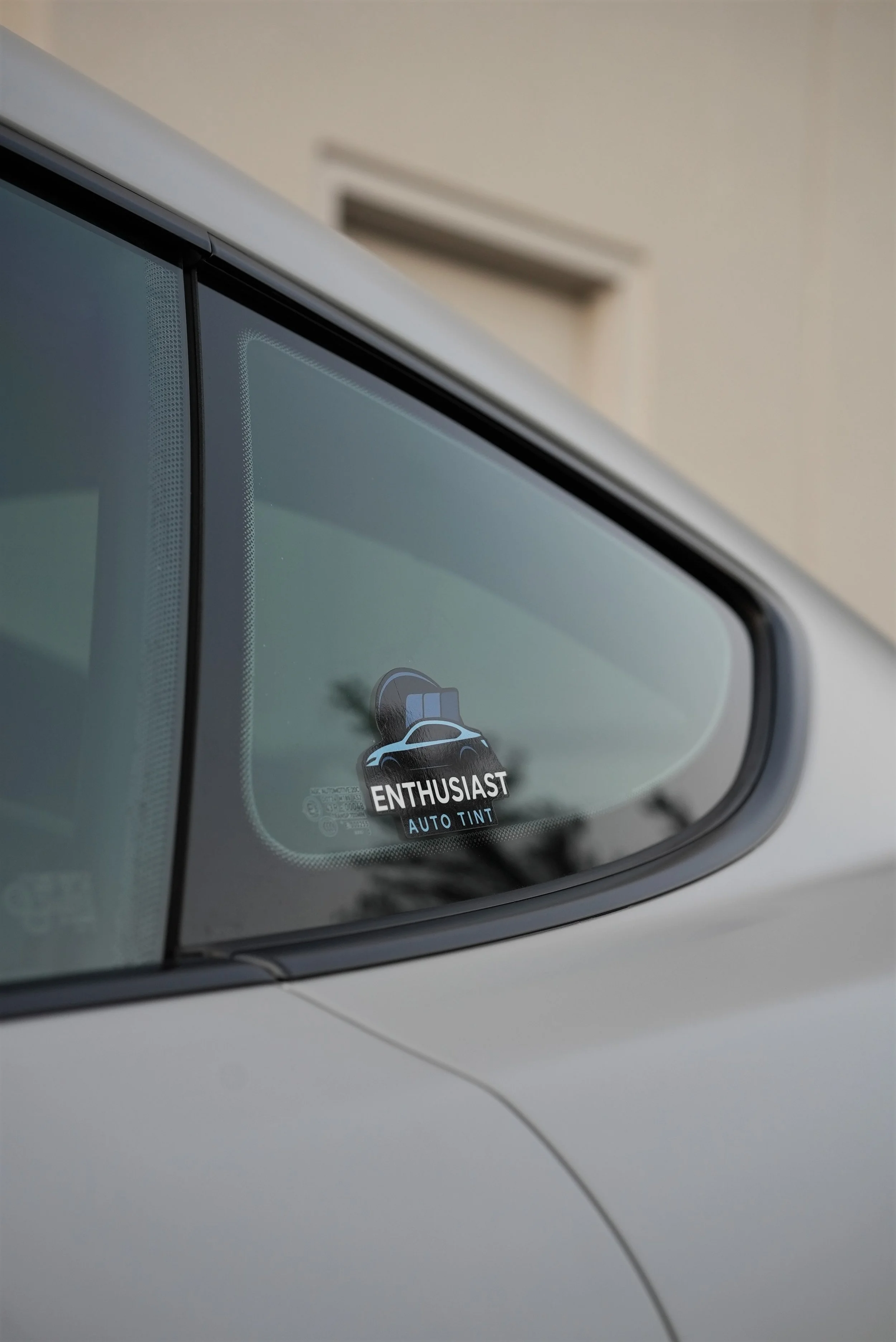 Close-up of a vehicle windshield featuring Enthusiast Auto Tint branding in Campbell, representing premium ceramic window tint and paint protection film installation for Tesla, luxury, and performance vehicles.