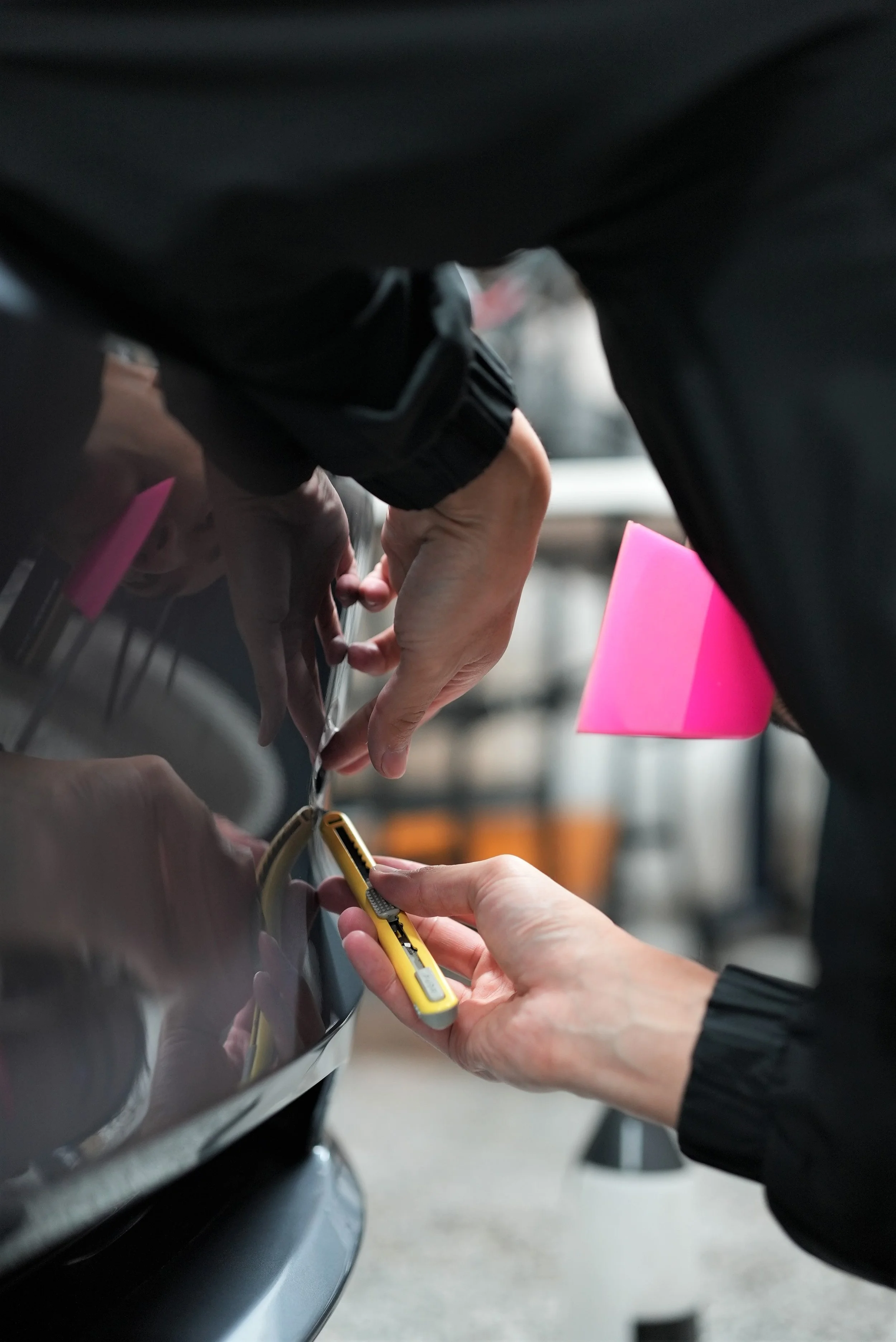 Close-up of hands connecting a charging cable to a car's charging port.