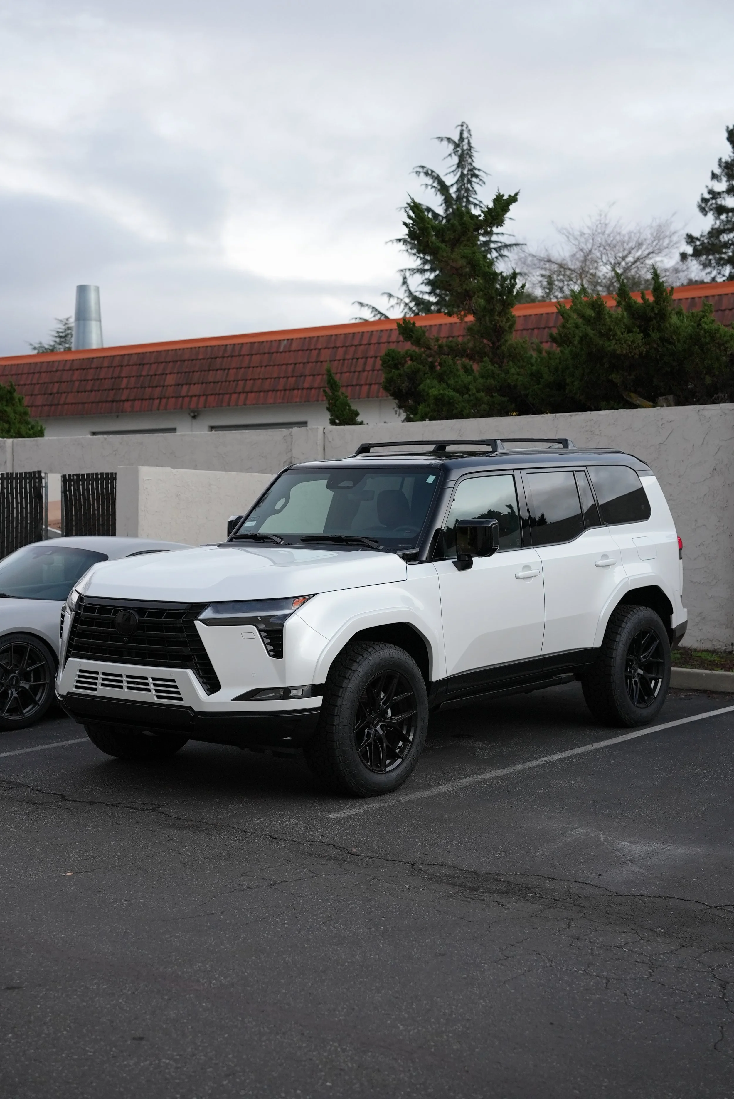 White luxury SUV parked outdoors near a modern building in Silicon Valley, representing premium vehicle protection services including ceramic window tint, paint protection film, and ceramic coating by Enthusiast Auto Tint in Campbell.