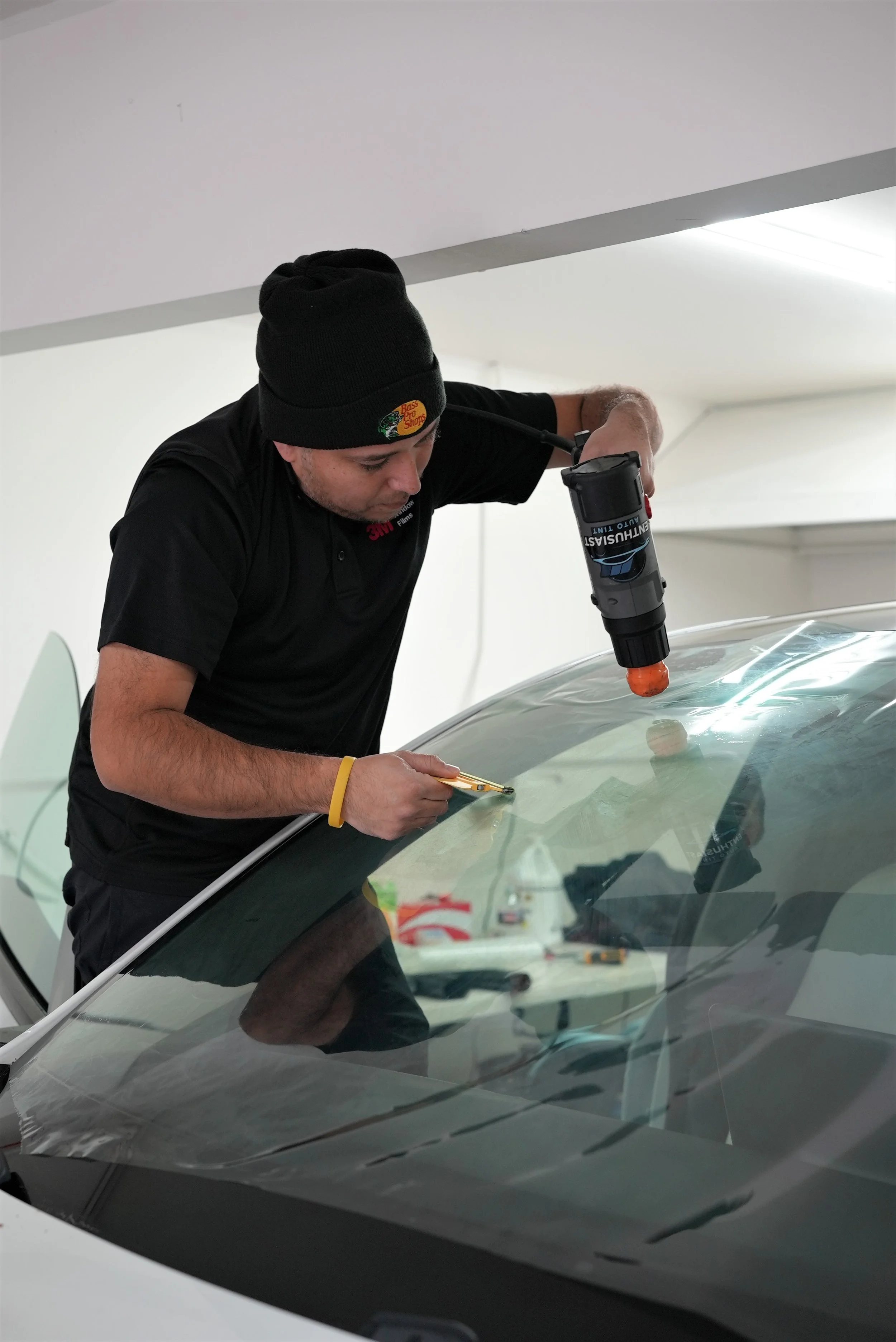 Professional ceramic window tint installation on a vehicle windshield using precision heat-shrinking techniques inside a controlled automotive workshop in Campbell, specializing in premium Tesla, luxury, and performance vehicle protection services by