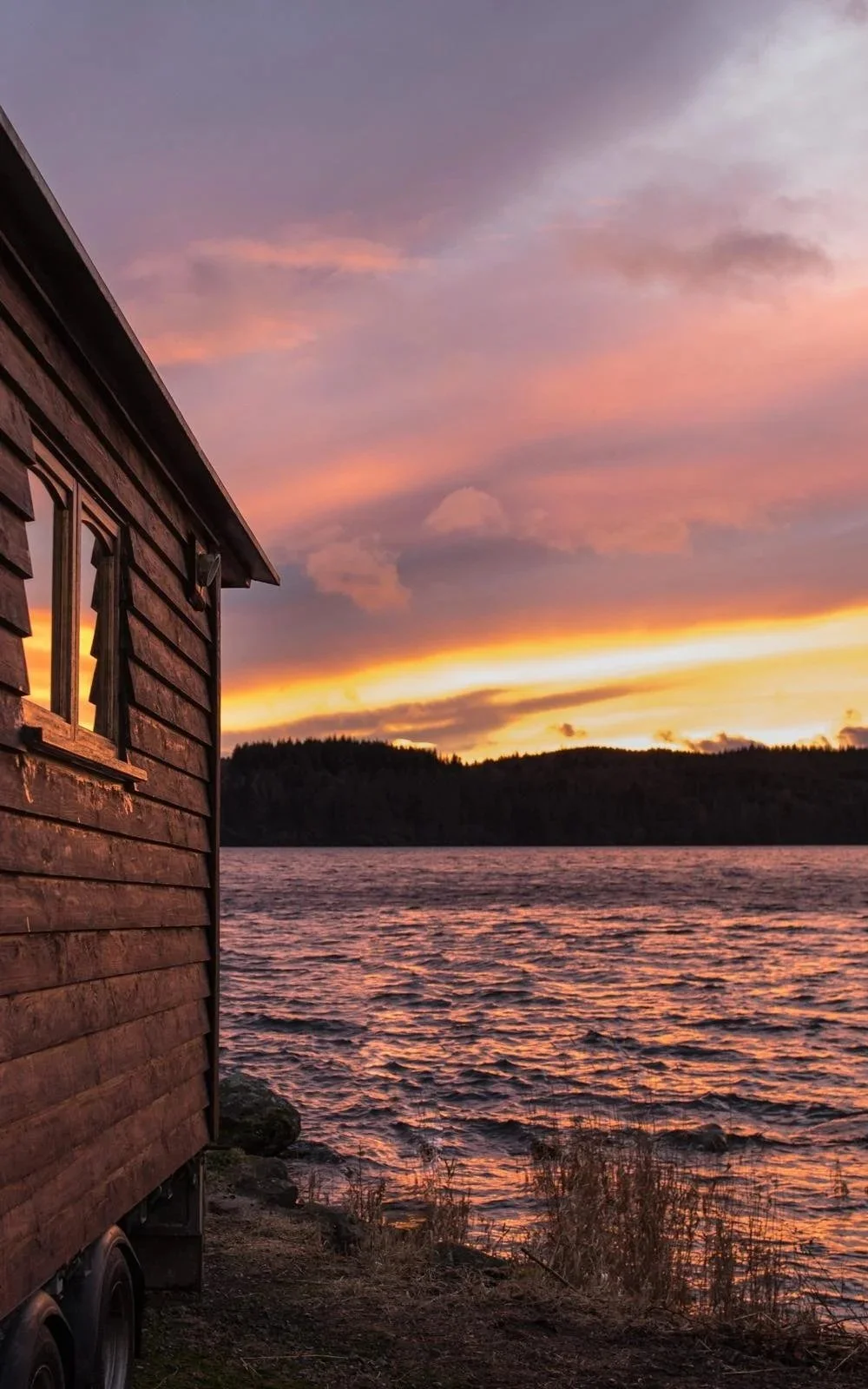 A sauna overlooking Loch Venachar with a pink sunset