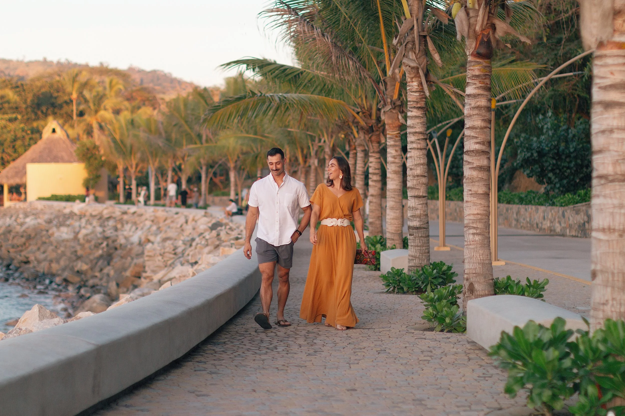 Man and woman walking at sunset along boardwalk in zihuatanejo Mexico.