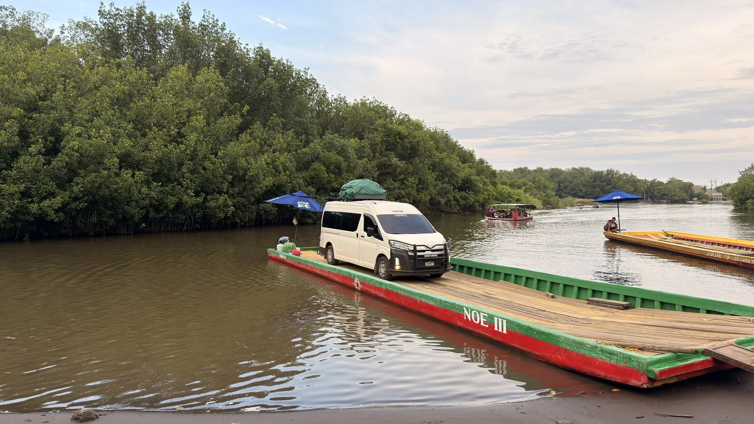 Shuttle van crossing a mangrove lagoon on a wooden barge into El Paredón, Guatemala