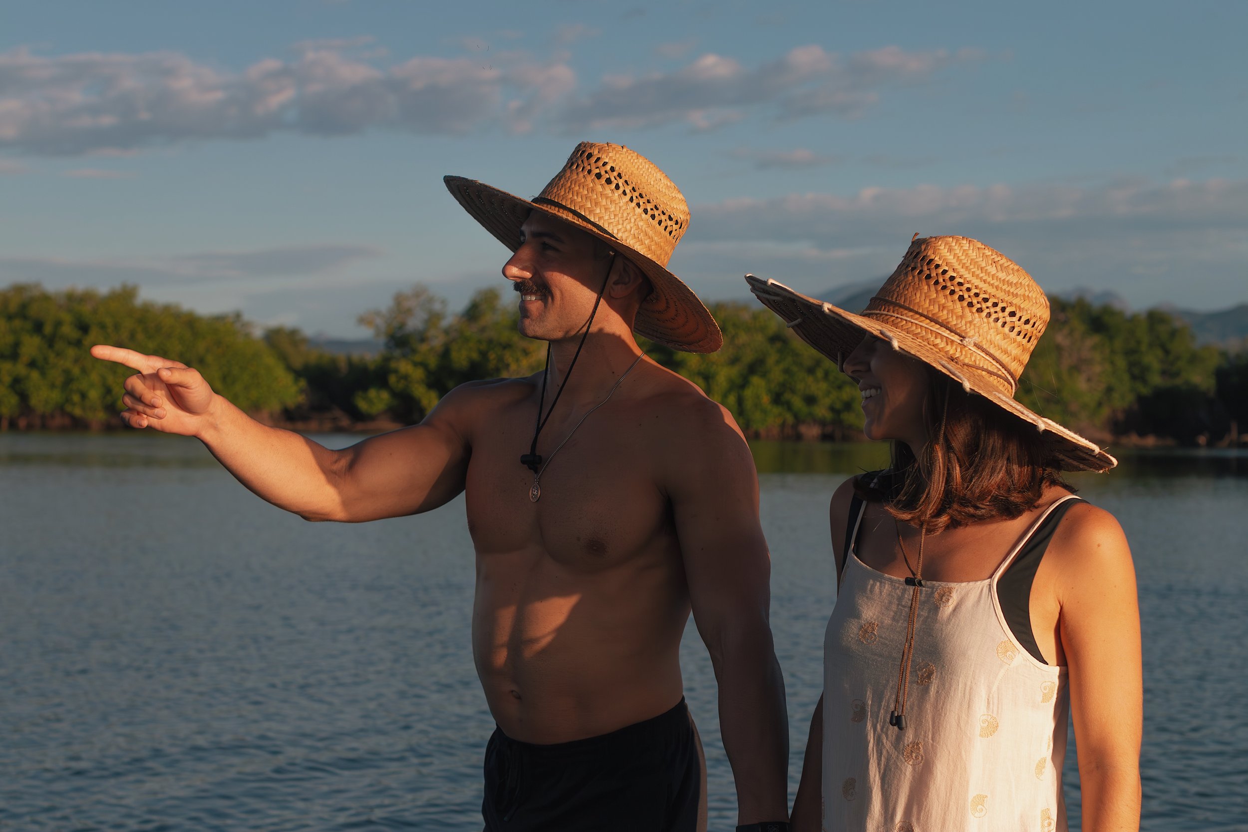 Shirtless man pointing in lagoon accompanied by woman in zihuatanejo mexico.