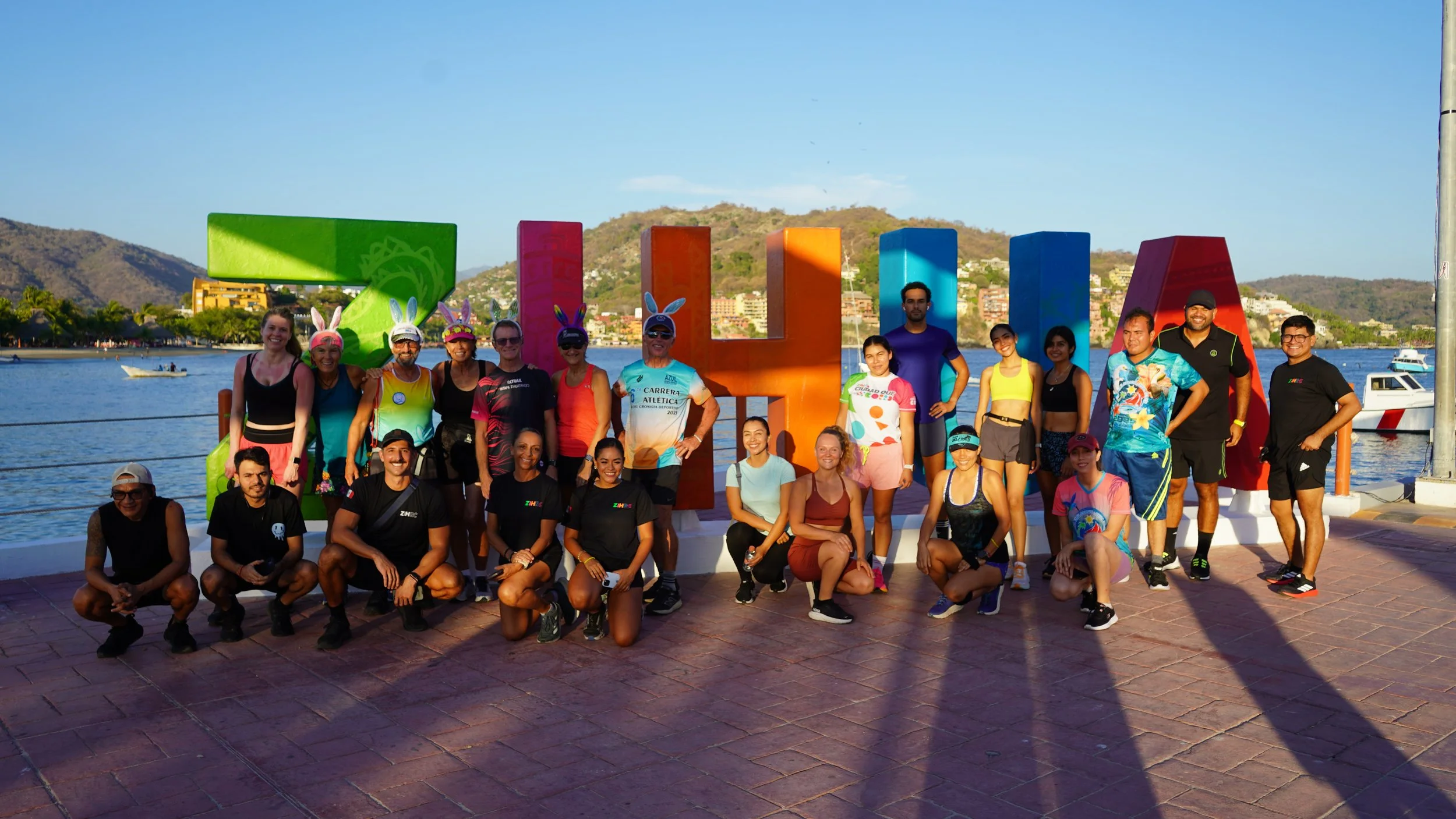 zihrc runners in front of painted ZIHUA sign on muelle of zihuatanejo mexico