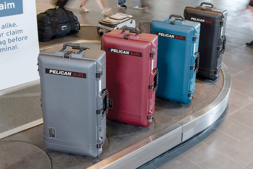 Four Pelican Air hard cases in gray, red, blue, and black colors displayed on airport baggage carousel.