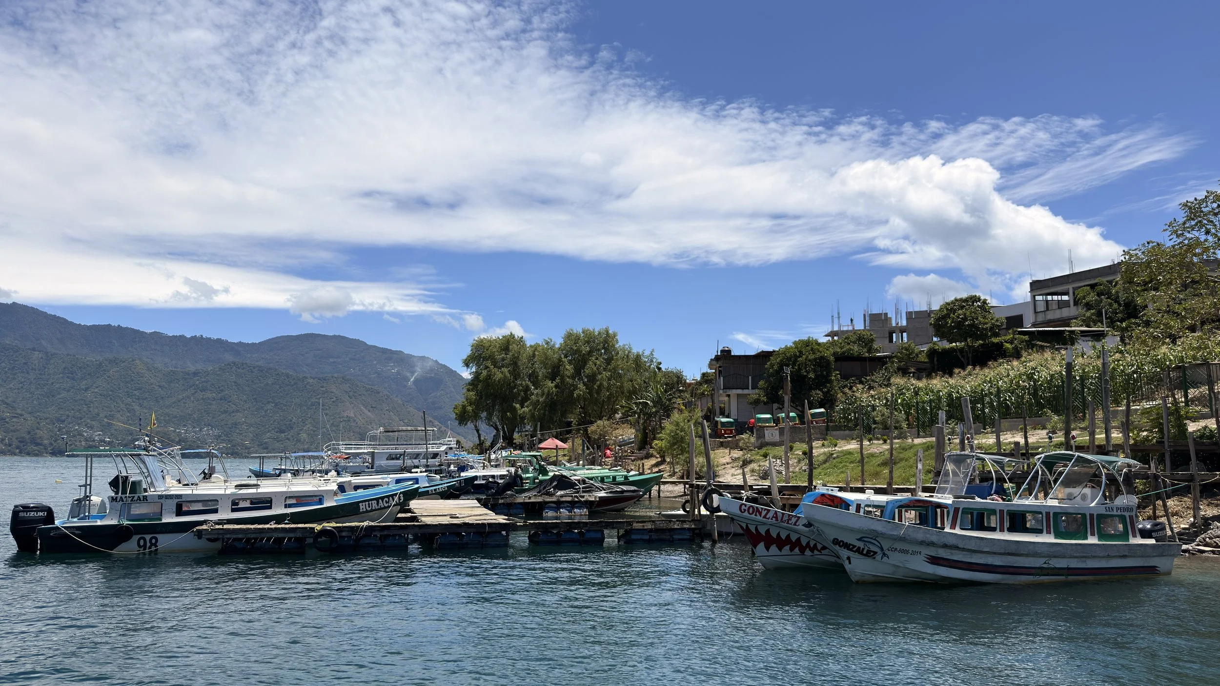 Boats docked at a pier on Lake Atitlán with green hillsides behind, Guatemala