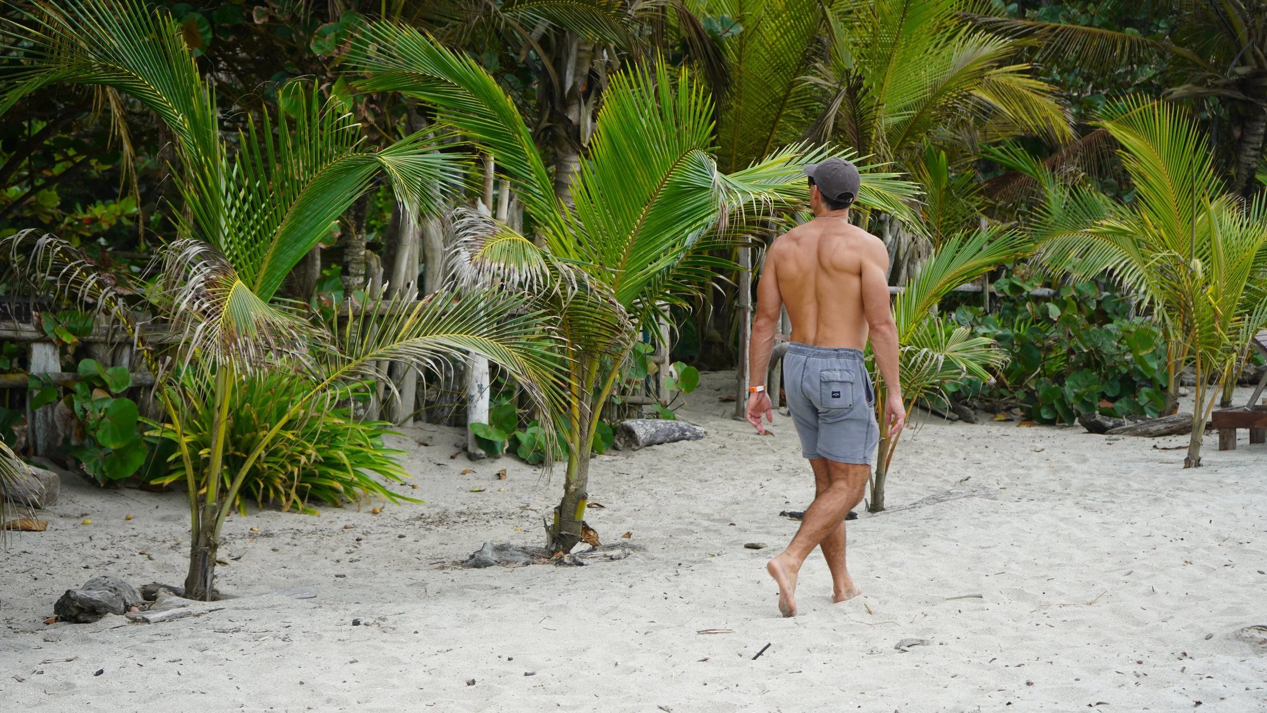 Buff man walking along beach in Santa Marta, Colombia.