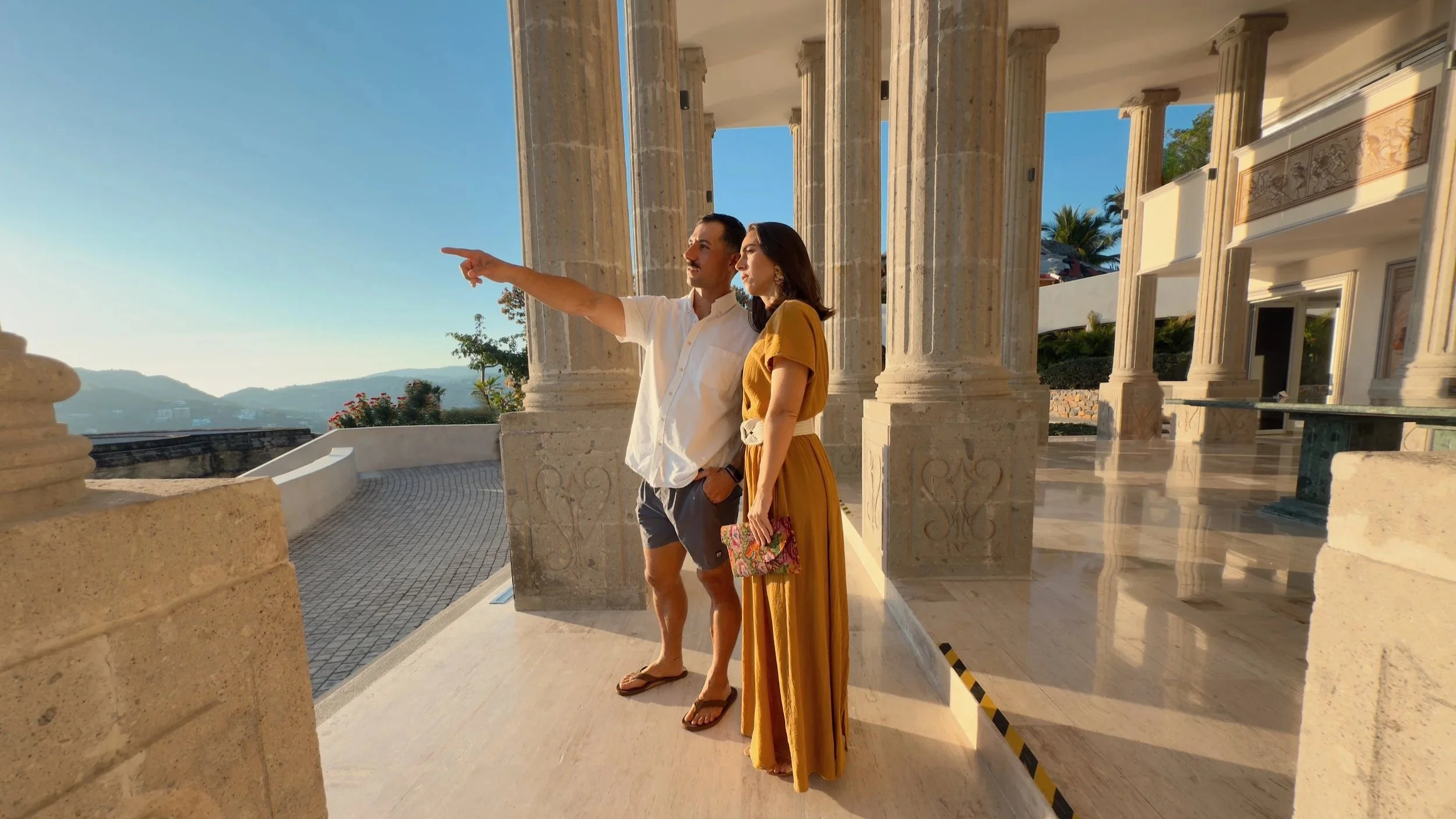 Mustached man and woman pointing at sea from columns of parthenon zihuatanejo mexico.
