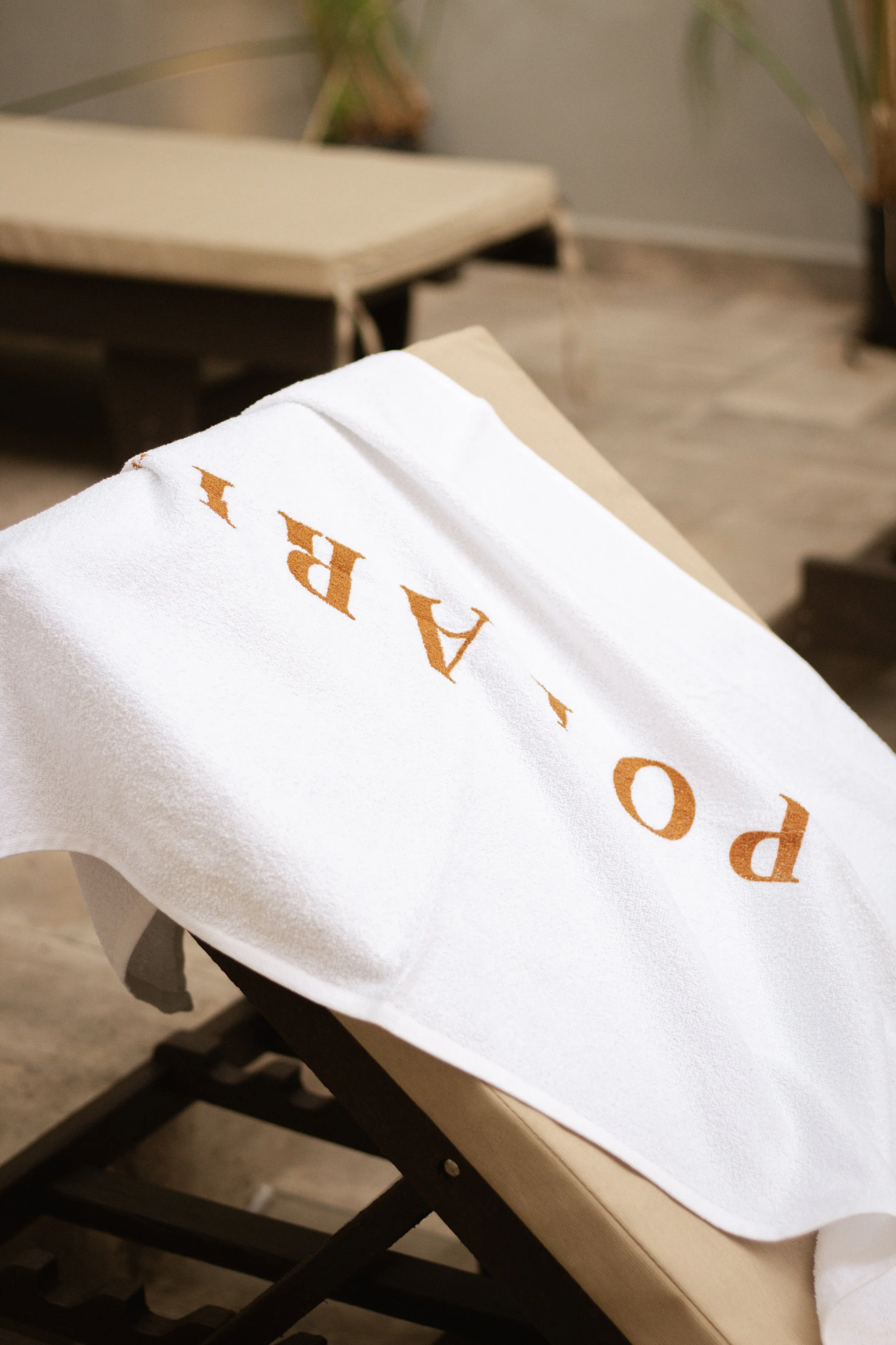 Close-up acercamiento de una toalla blanca con letras anaranjadas que dicen "Polari", que es el mejor sauna gay de Guadalajara