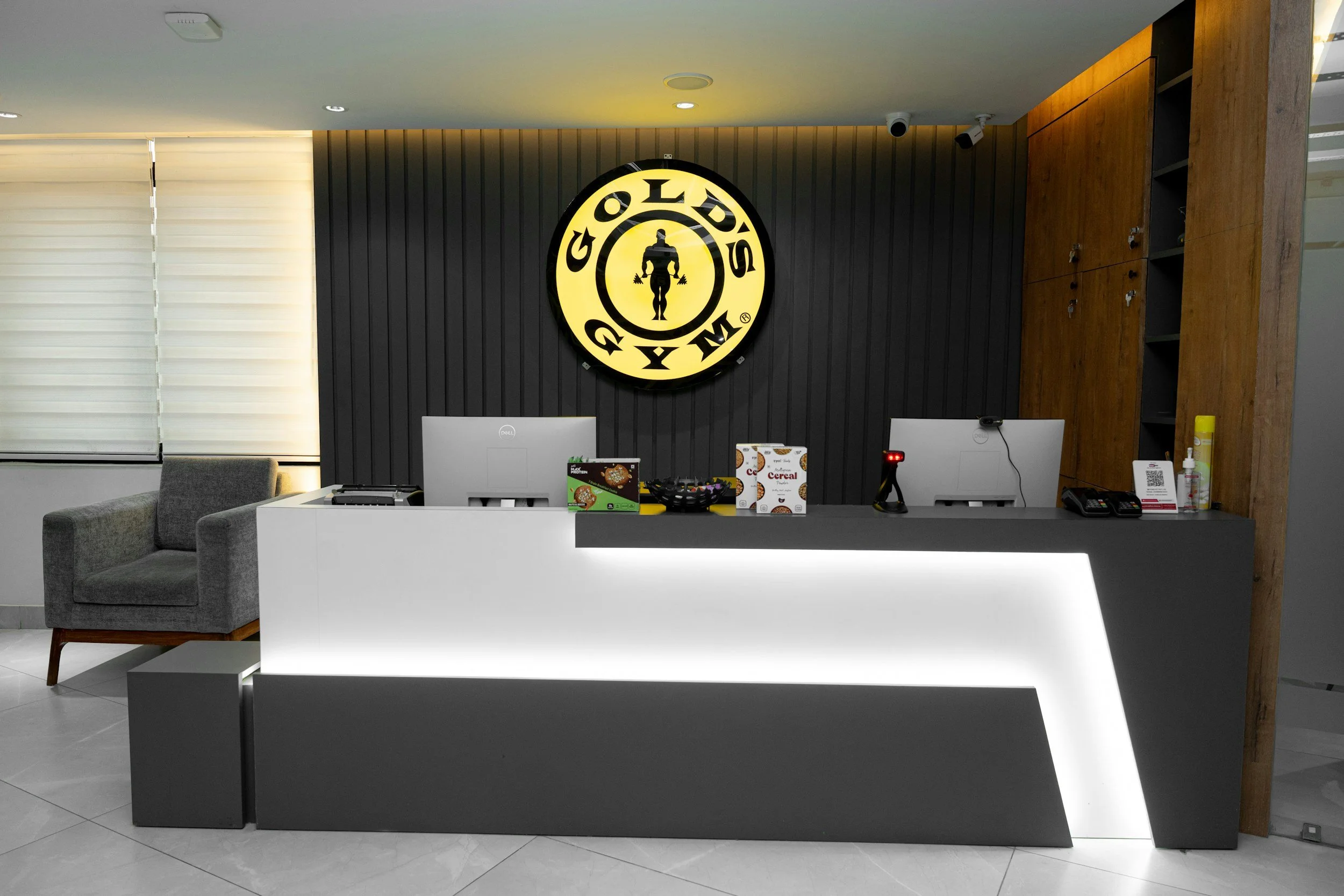 Front desk of a Gold's Gym with the gym's circular logo on a dark wall.