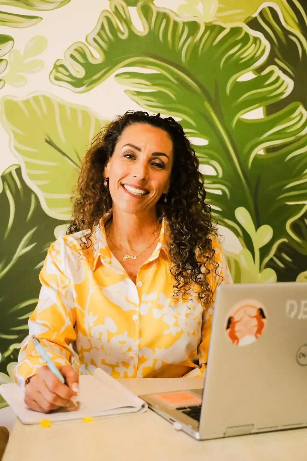 Debi Borger with laptop and natural green background
