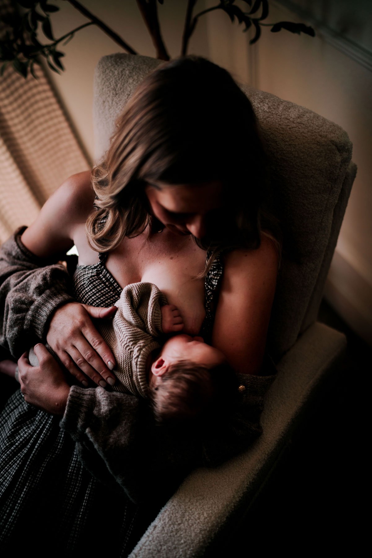 A woman breastfeeding a baby while sitting in a comfortable armchair.