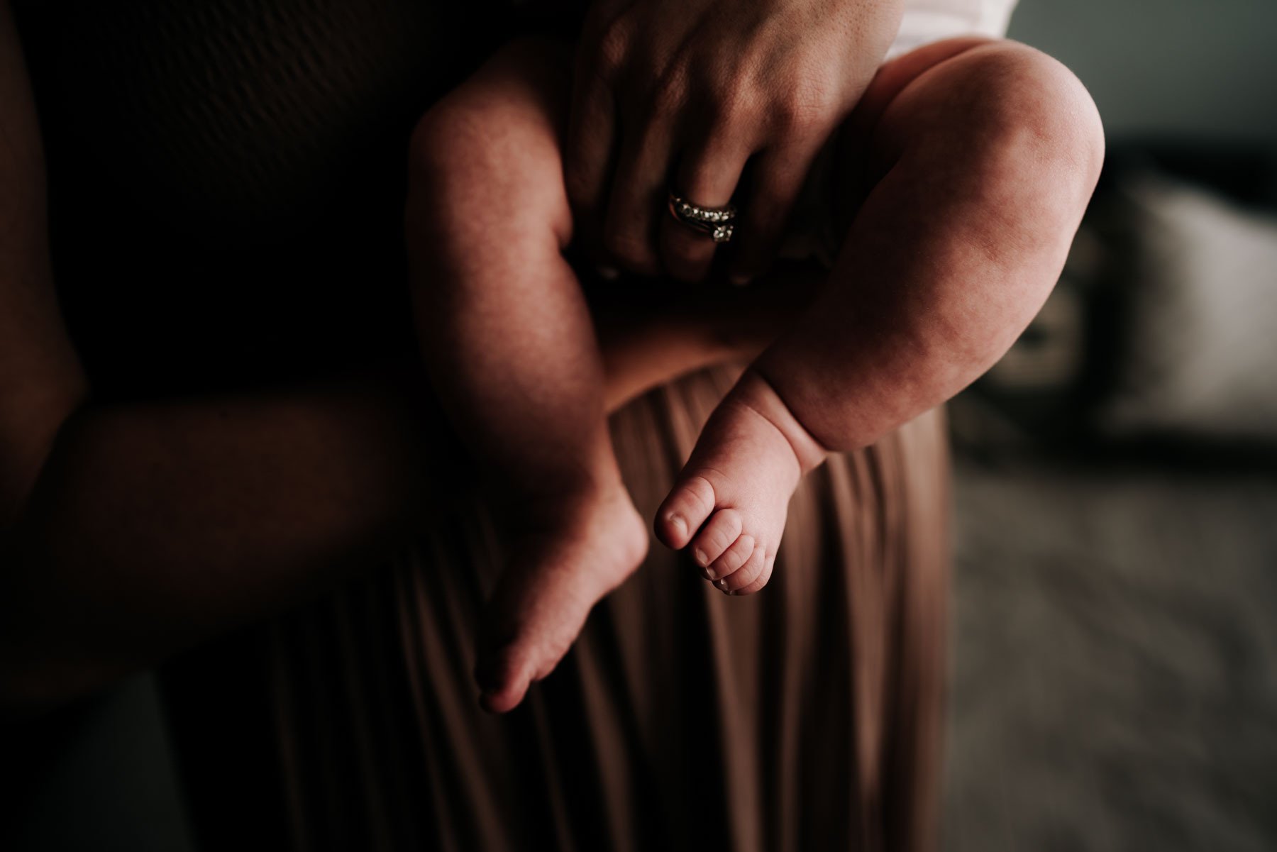 A mother is holding her newborn baby and the image is just the baby's feet.
