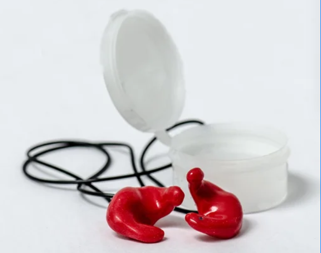 Red earplugs with a clear case and black cords on a white background.