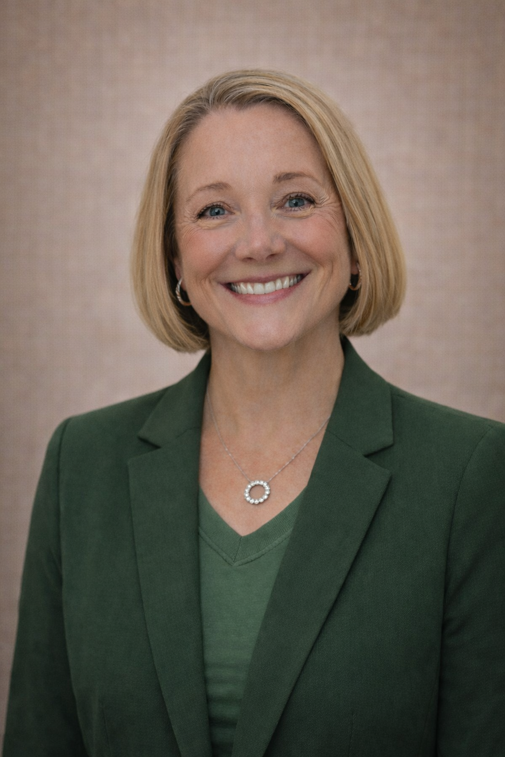 Debbie smiling at the camera wearing a dark green blazer.