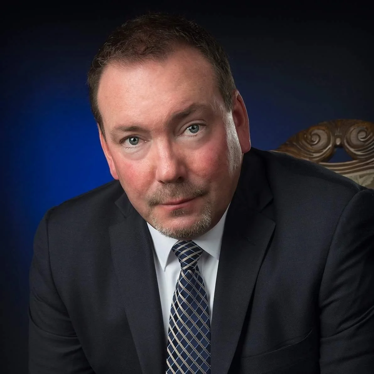 TD looking at the camera wearing a dark suit and tie.