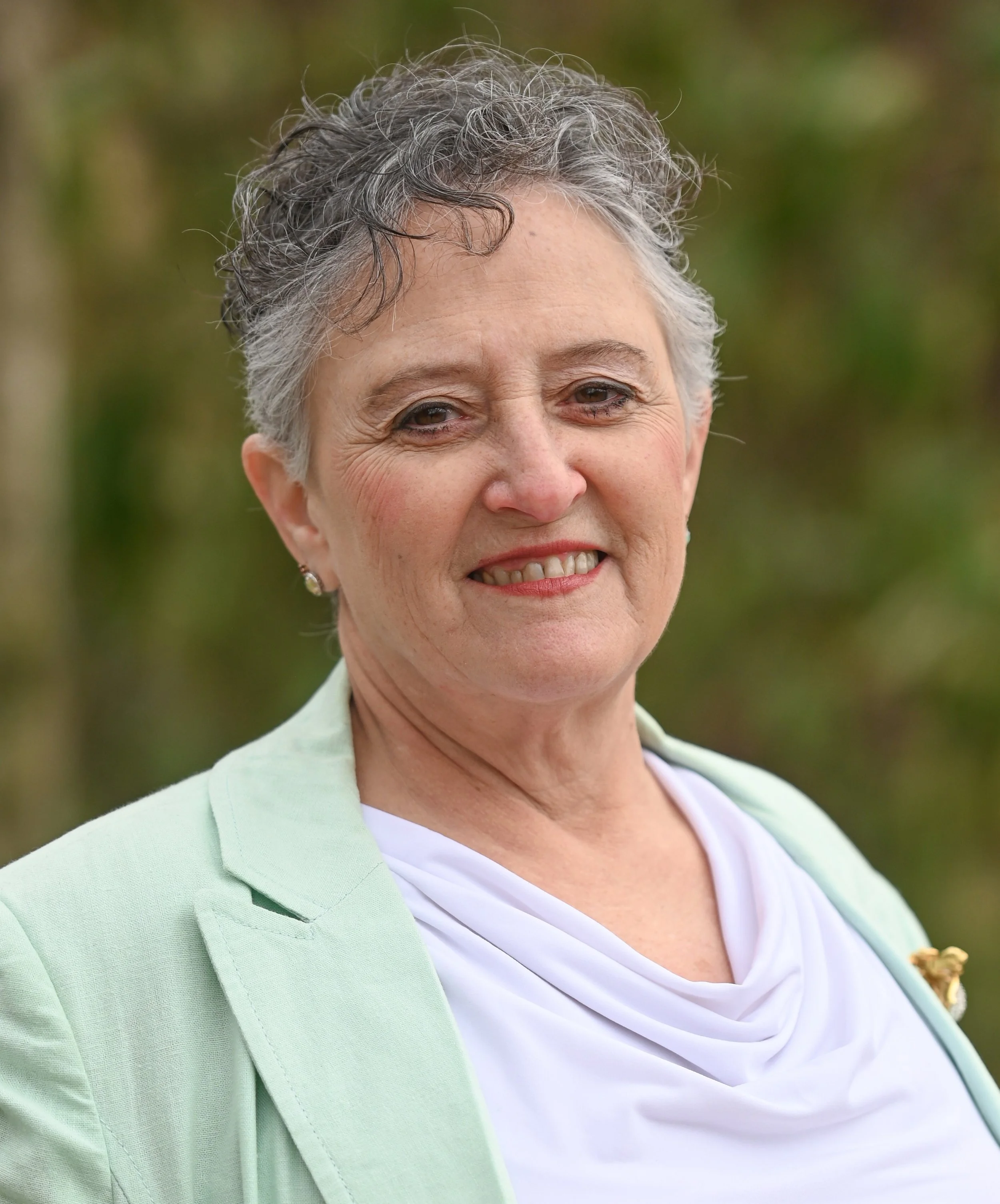 Bonita smiling at the camera wearing a light green blazer.