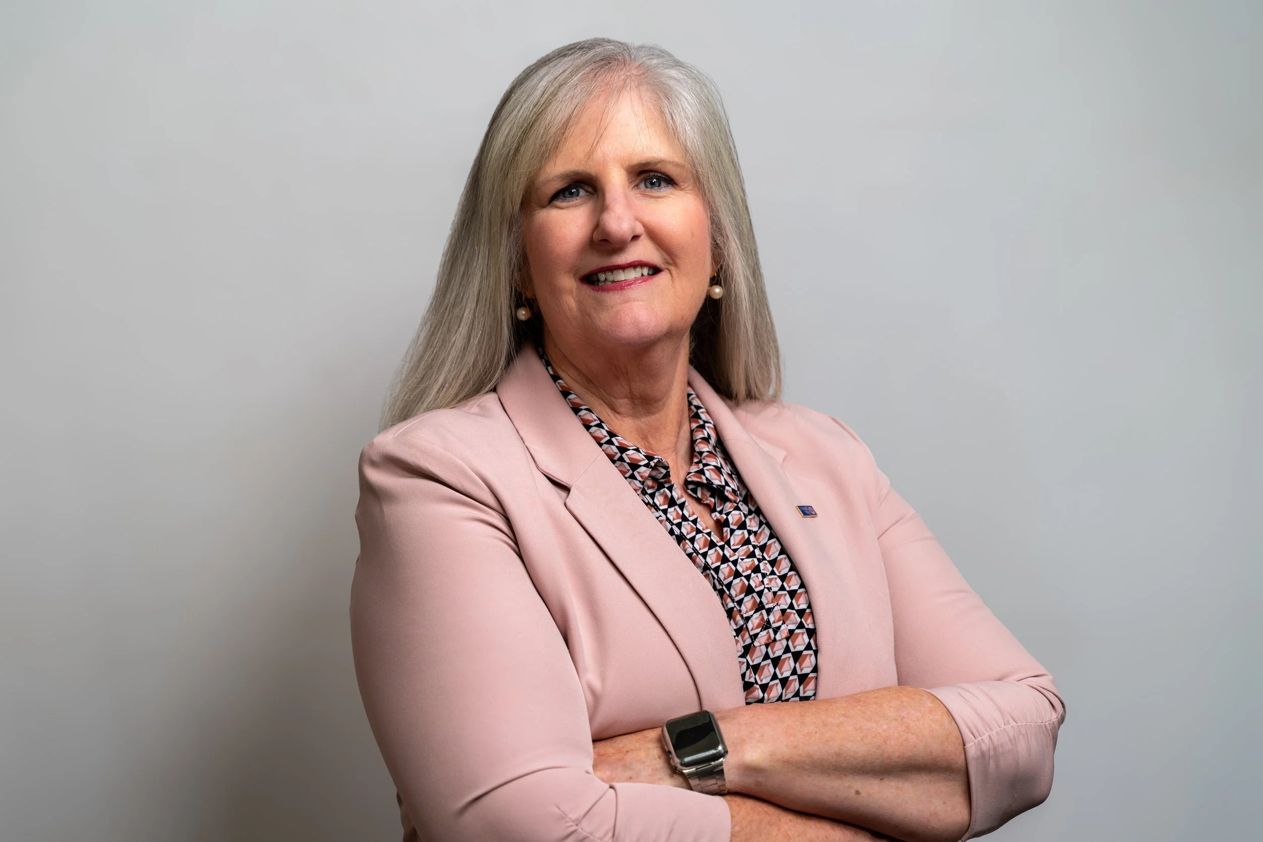 Melissa smiling at the camera wearing a light pink blazer.