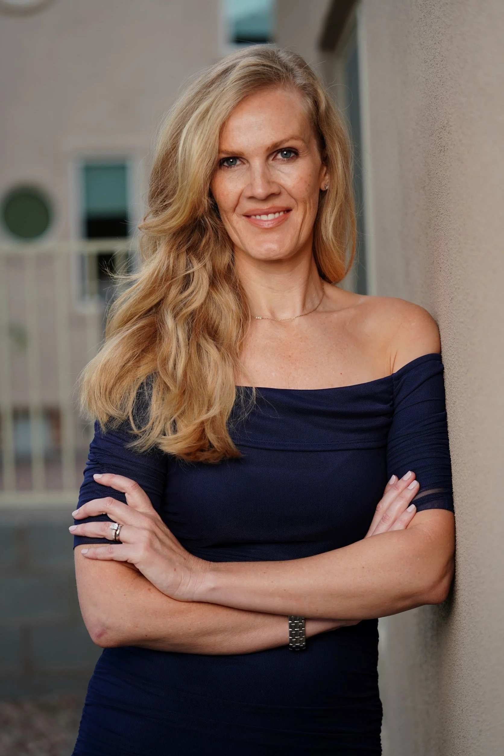 Andrea smiling at the camera wearing an off the shoulder dark blue dress.