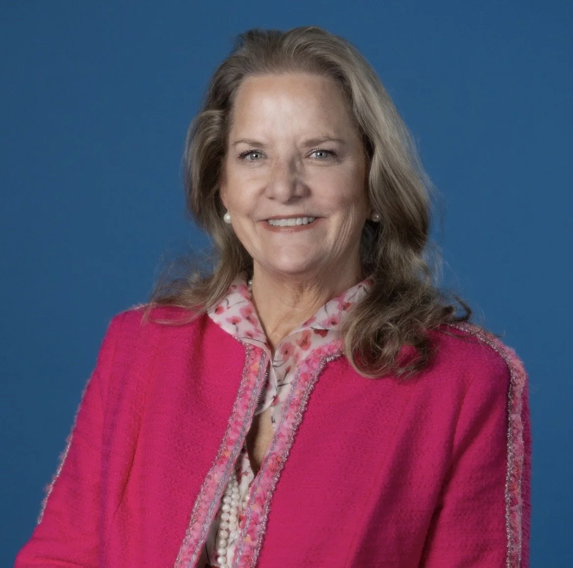 Kyle smiling at the camera wearing a pink blazer.