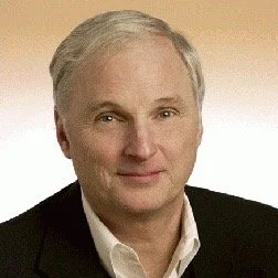 Professional portrait of Dennis McMillian wearing a suit and looking towards the camera.