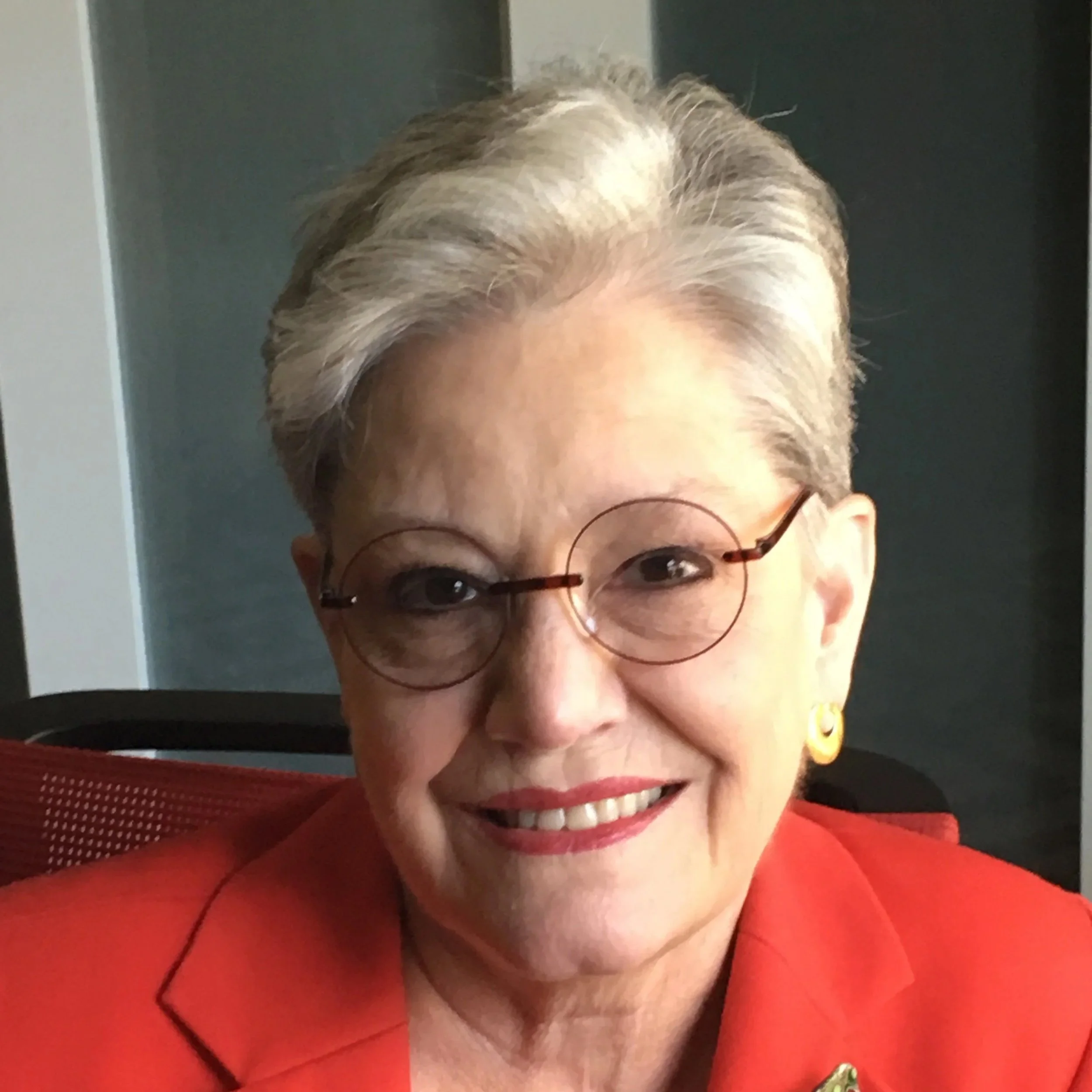 Photograph of Terry Tolan wearing red and smiling at the camera.