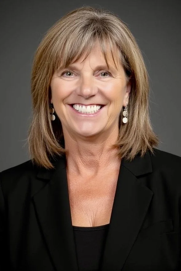 An image of Jodee smiling at the camera wearing a black blazer and top.