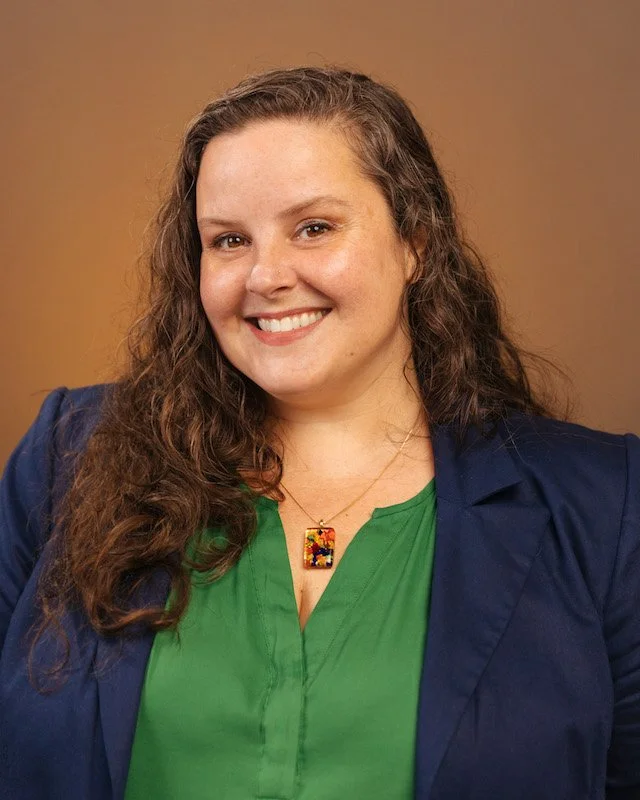 Brandy smiling at the camera wearing a blue blazer and green blouse.