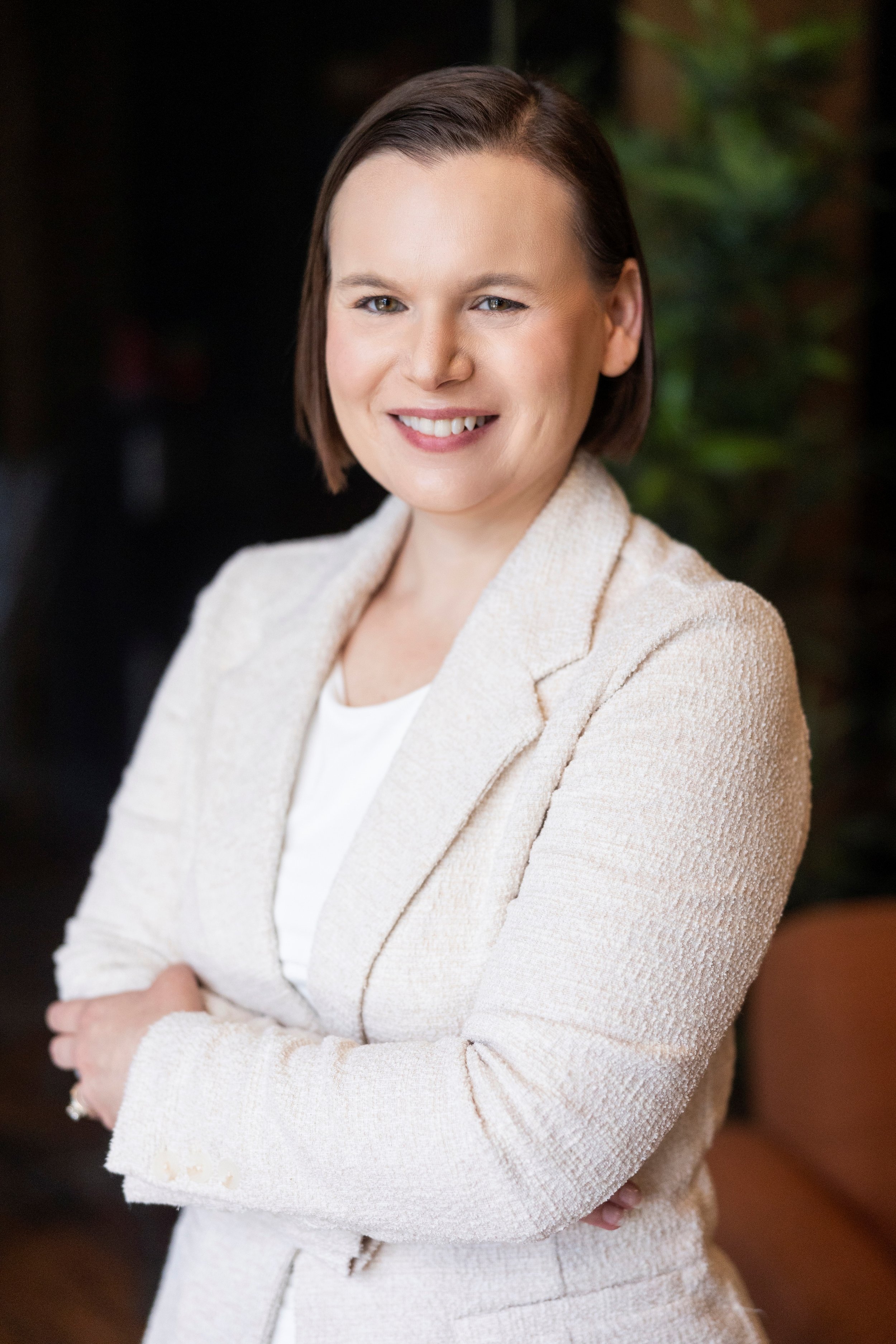 Angela smiling at the camera in a light colored suit.