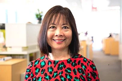 Kitty smiling at the camera wearing a colorful animal print shirt.